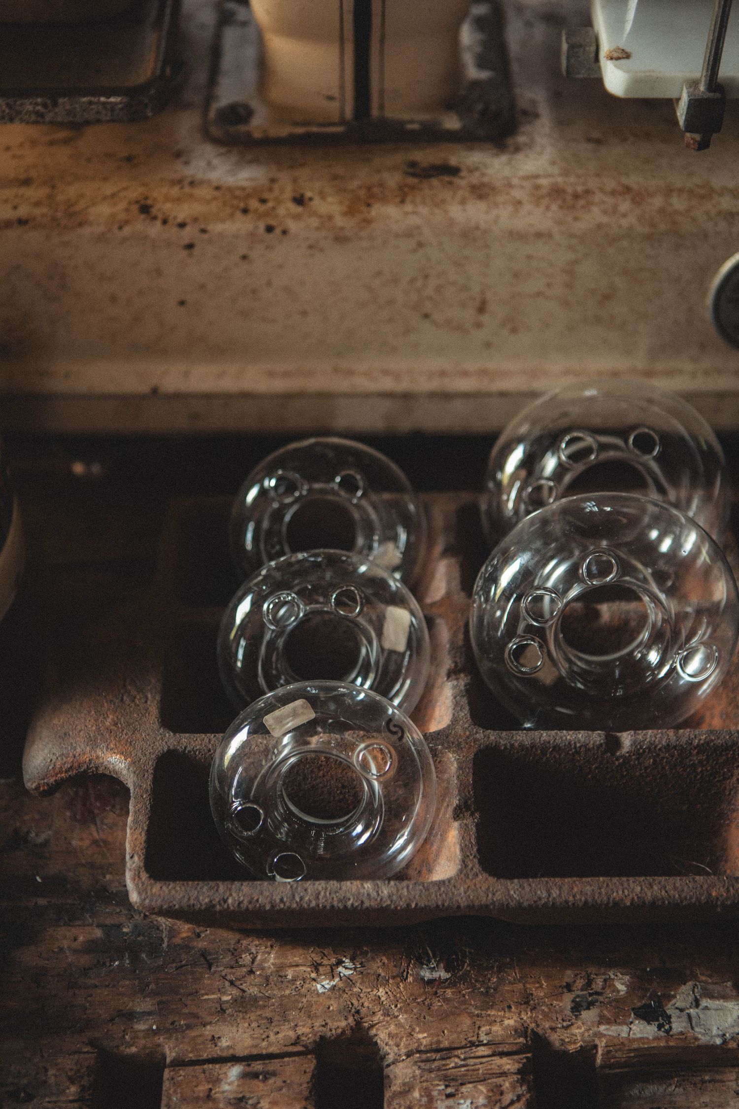 Collection of vintage glass domes arranged on wooden shelving in moody lighting.