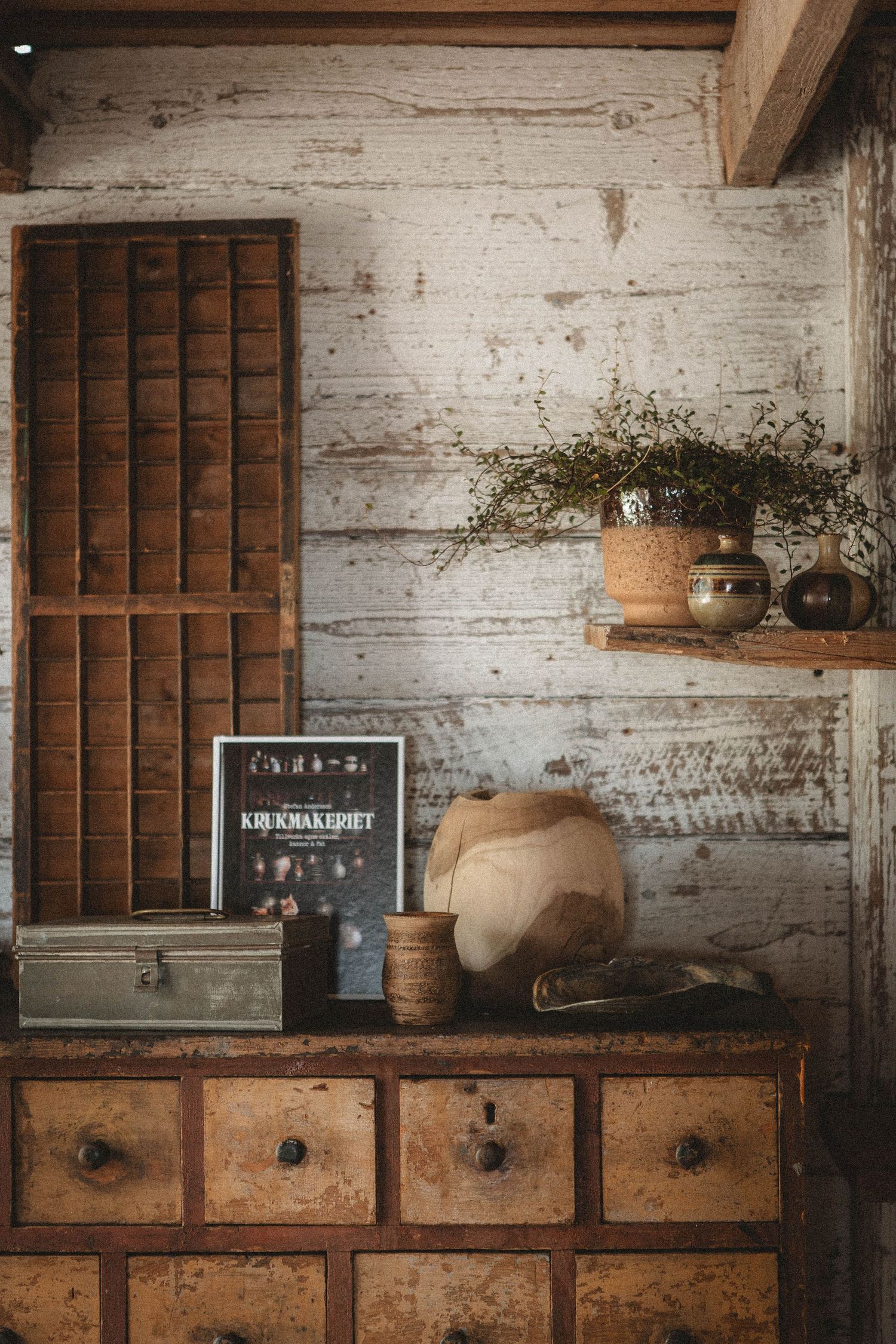 Vintage apothecary cabinet with rustic decor against weathered white wooden wall.