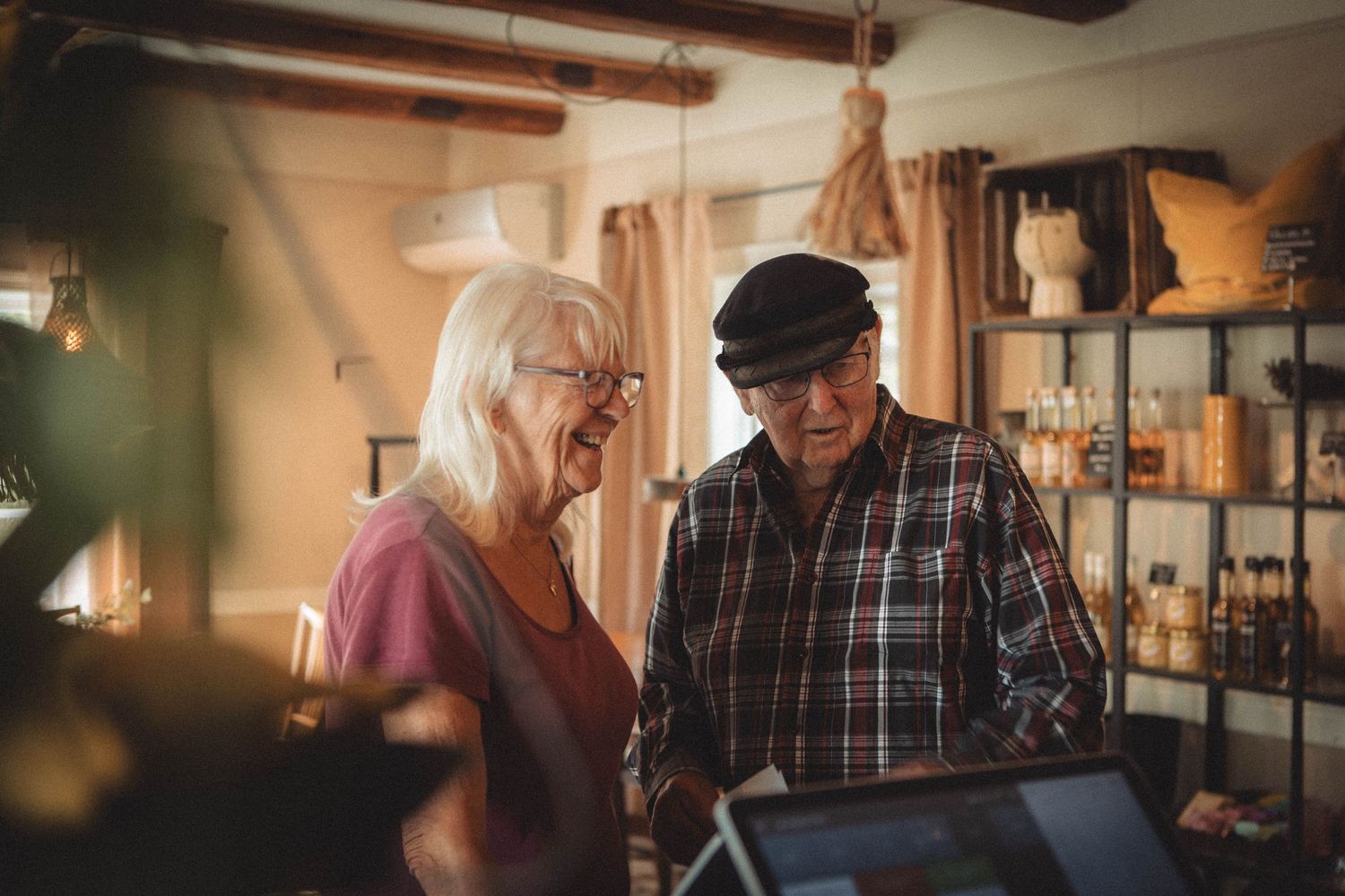 Two people interacting with a digital device in a warmly lit retail space.