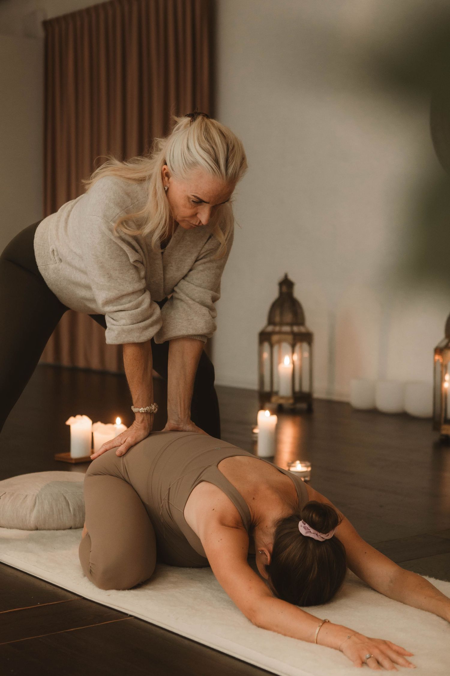 Professional massage therapist performs therapeutic massage treatment in a relaxing candlelit spa setting.
