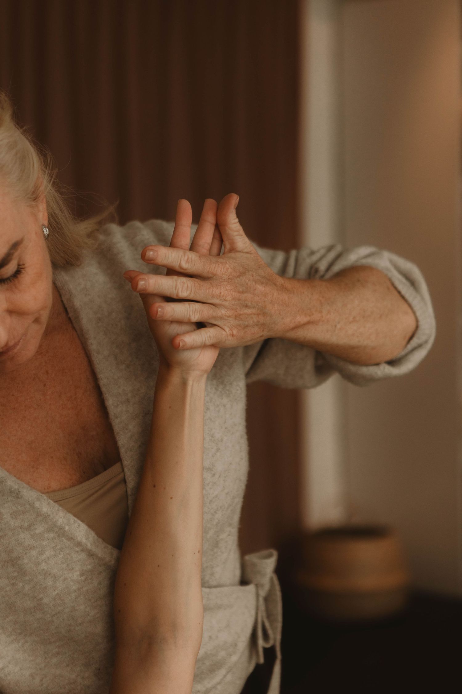 Close-up of hands performing therapeutic bodywork in a warm-toned treatment room.