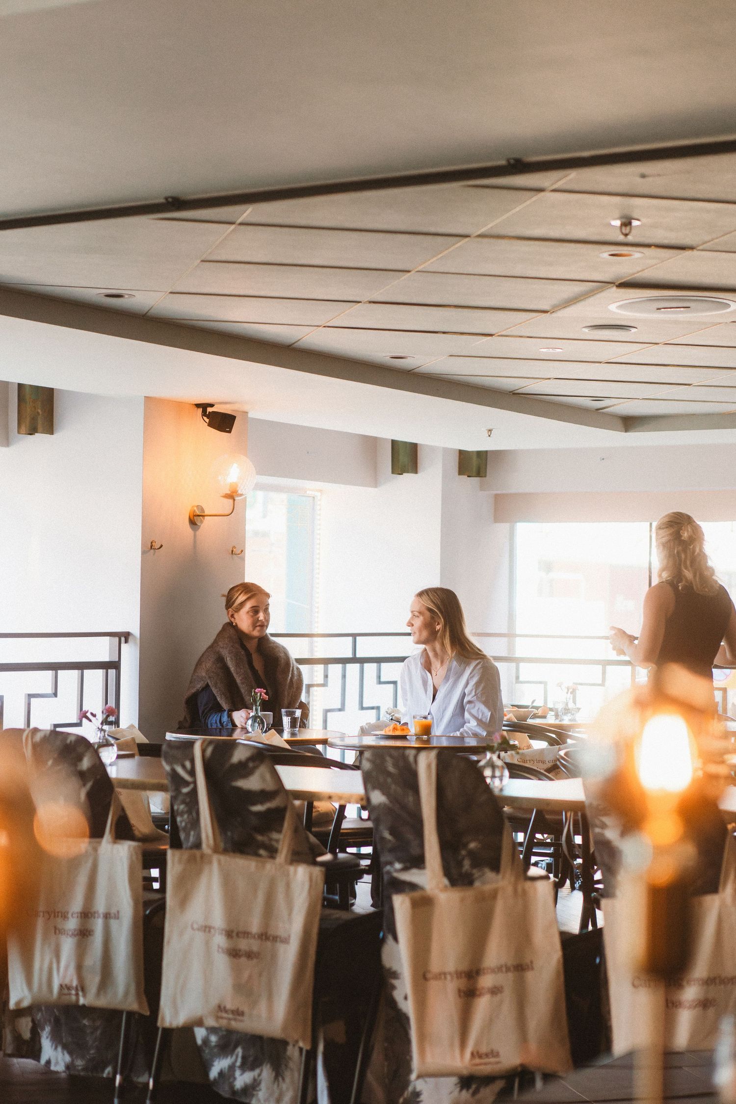 People seated at tables in a bright modern office or conference space with natural lighting.