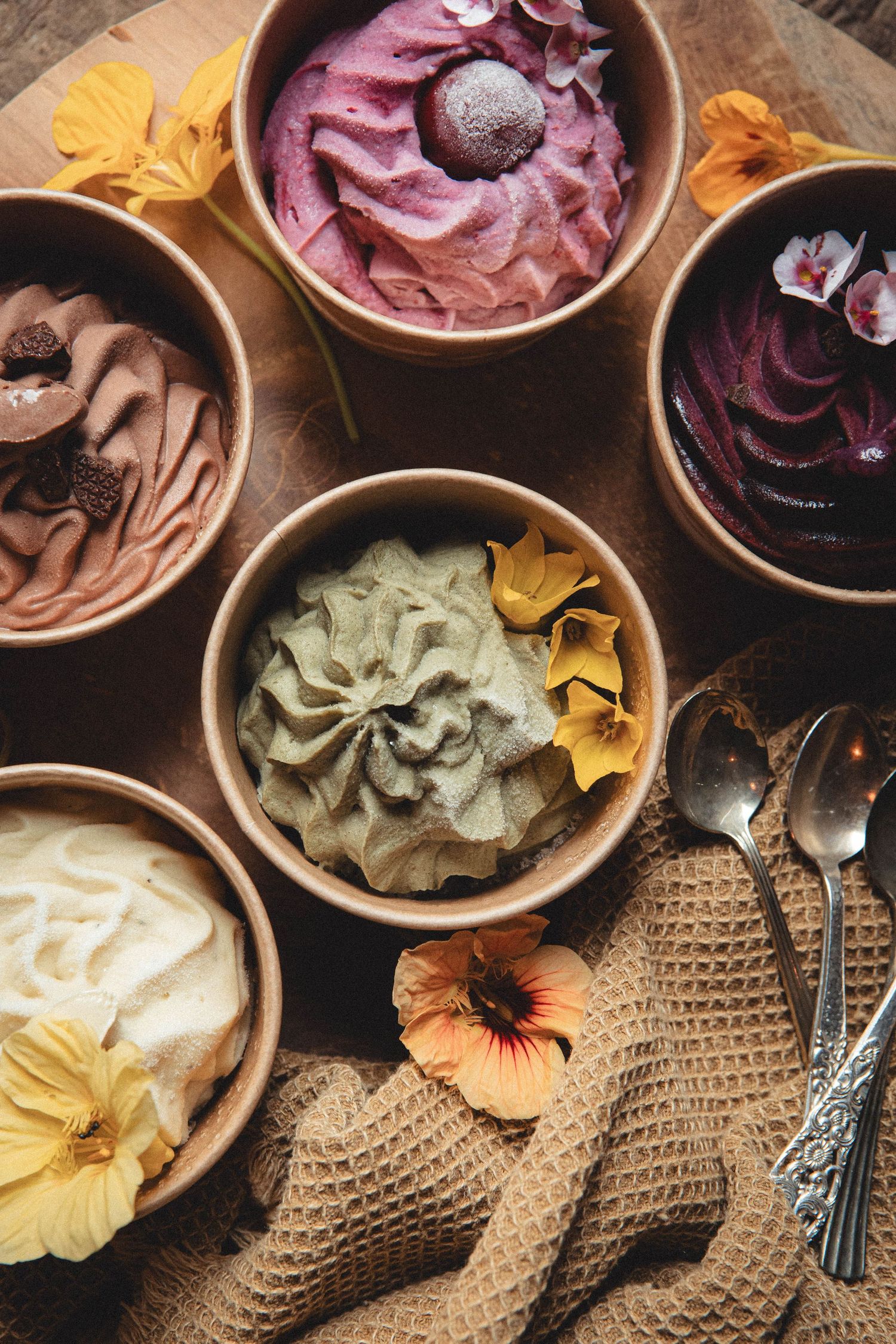 Artisanal ice cream in different flavors served in wooden bowls with floral decorations.
