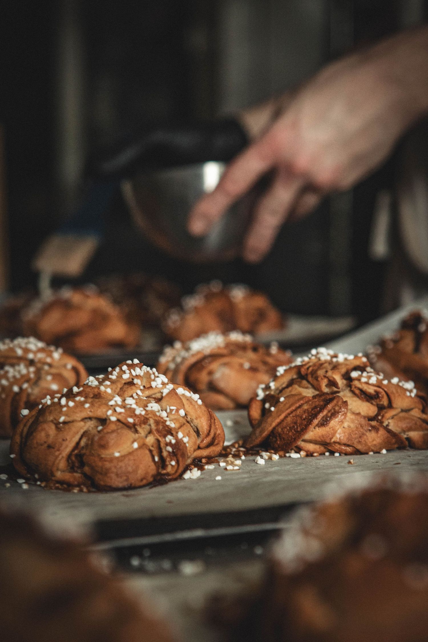 Homemade chocolate pastries with pearl sugar being prepared on a baking sheet.
