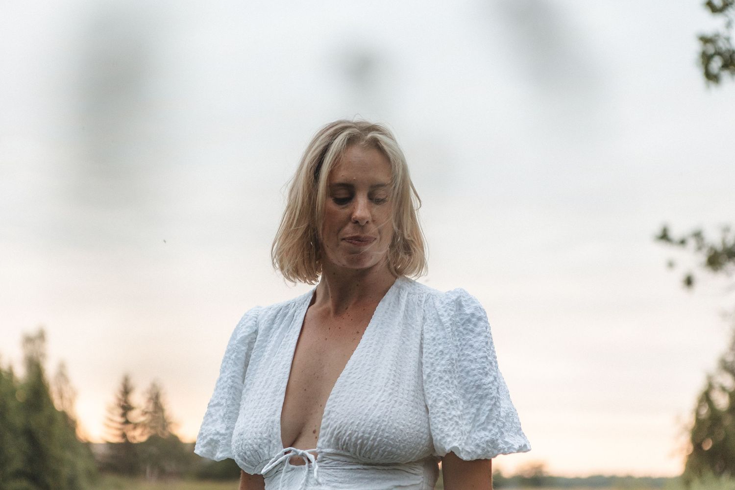 A romantic portrait in a white lace dress against a dusky summer evening sky.