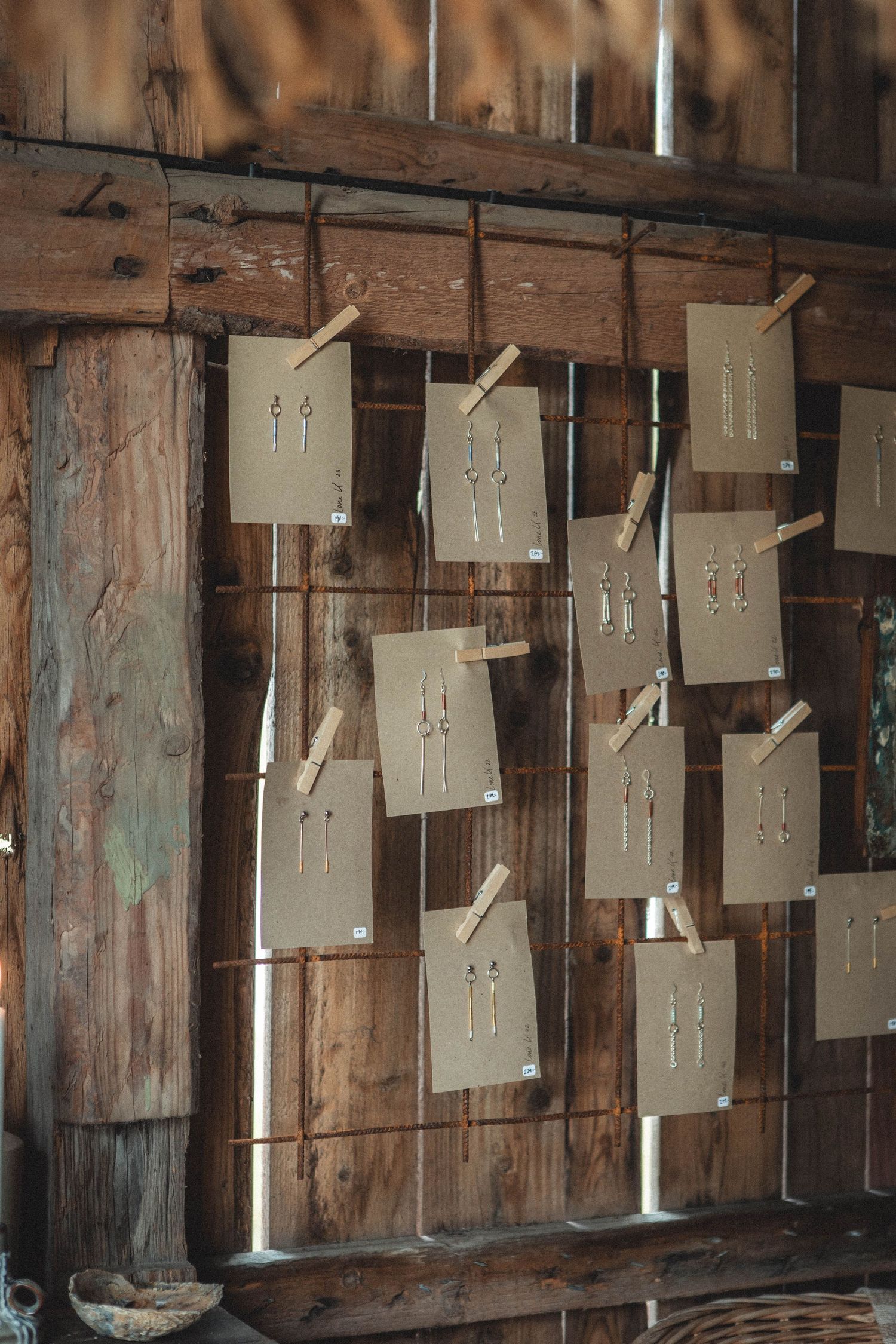 Brown paper cards with drawings hung on wooden wall in rustic interior setting.