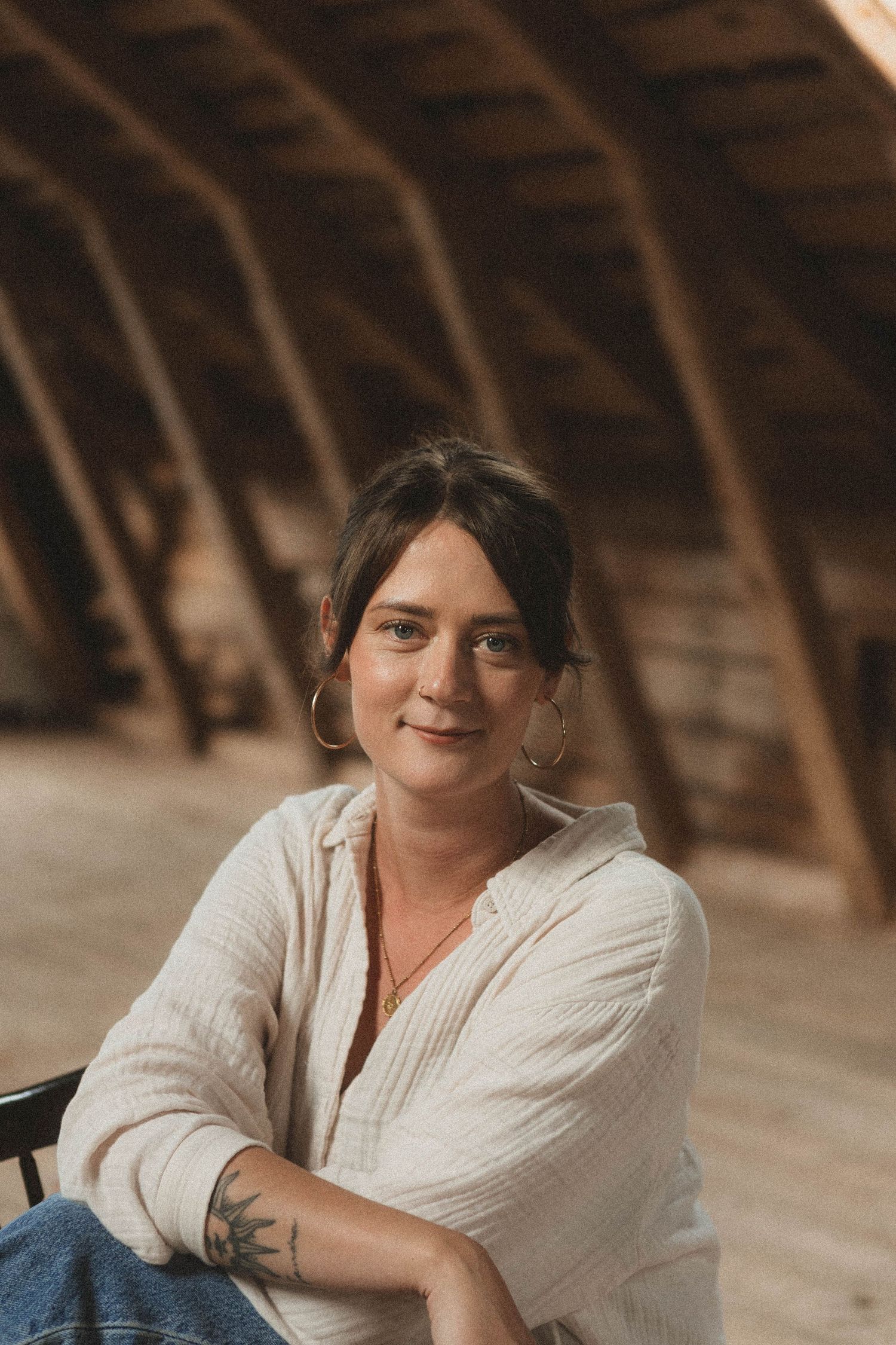 Person in casual white shirt sitting relaxed in an attic space with wooden beams.