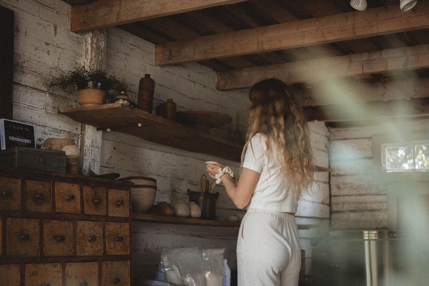 Person working in rustic kitchen with vintage wooden storage cabinets.