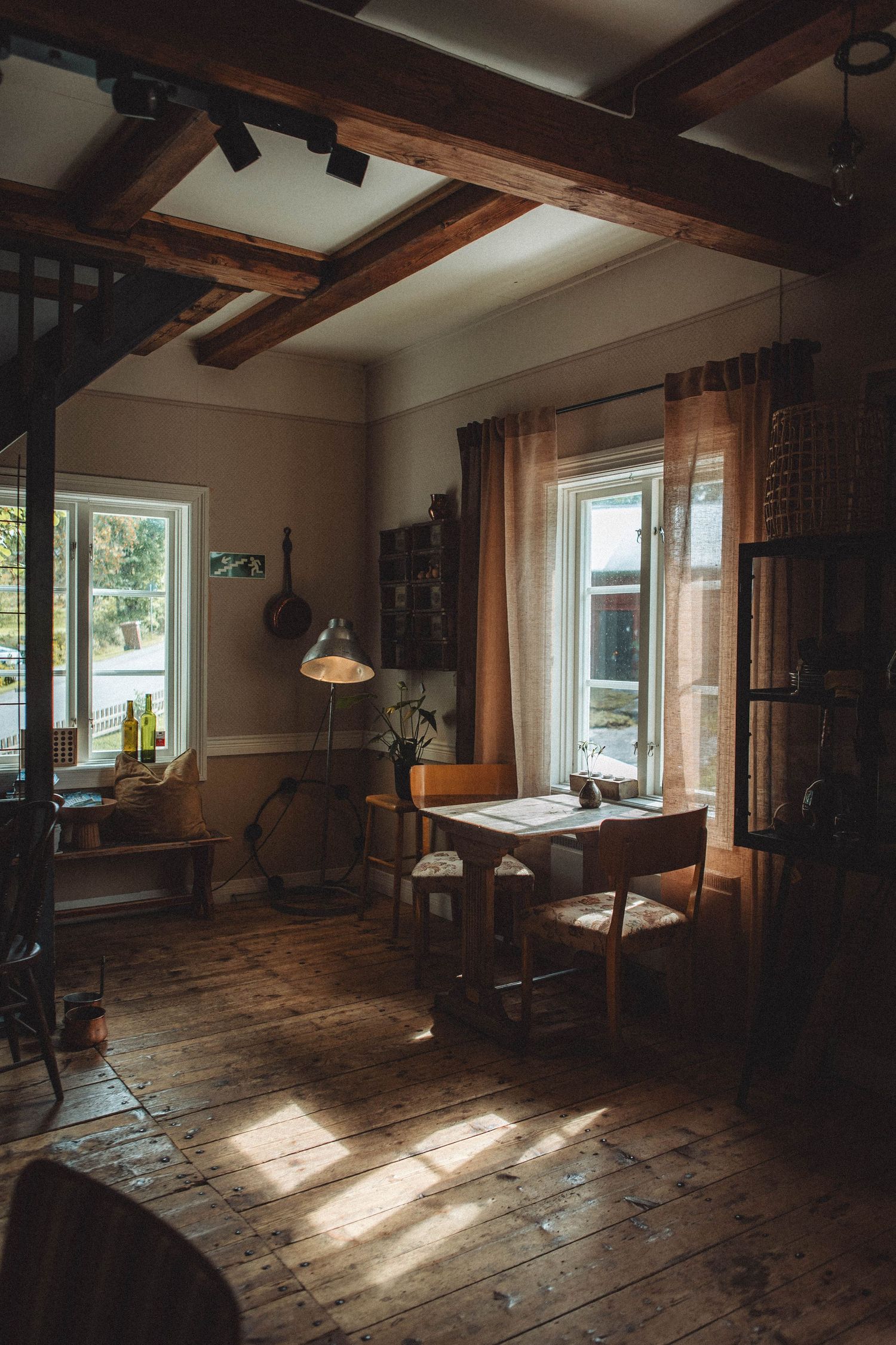 Sunlit room with wooden floors, exposed beams and vintage furniture creating a cozy atmosphere.