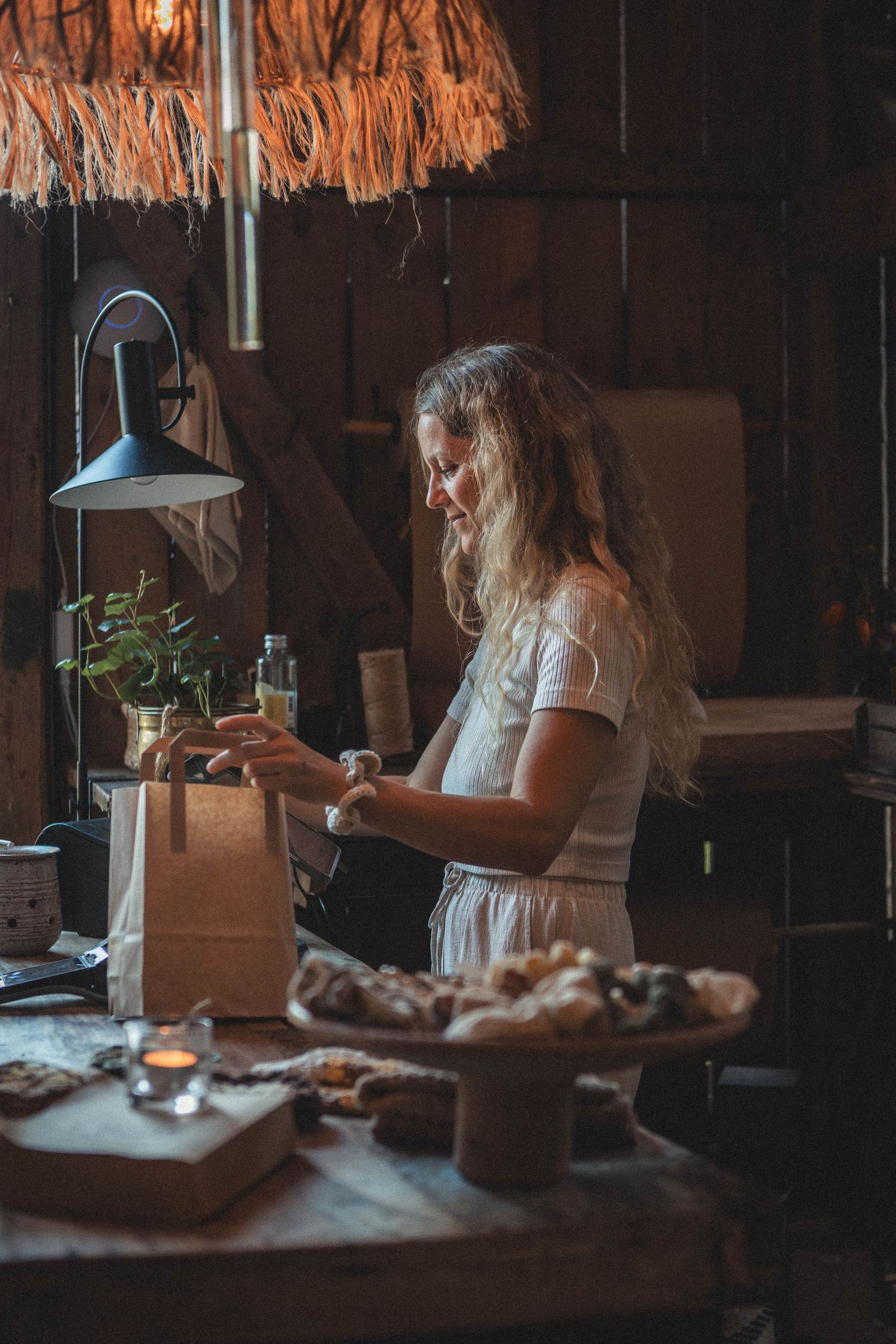 Rustic kitchen scene with antique lantern and person preparing items on a wooden counter.