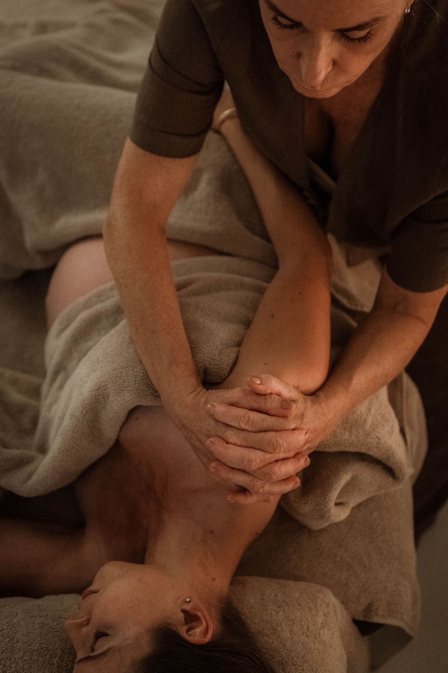 Close-up of therapeutic leg massage being performed on a massage table.