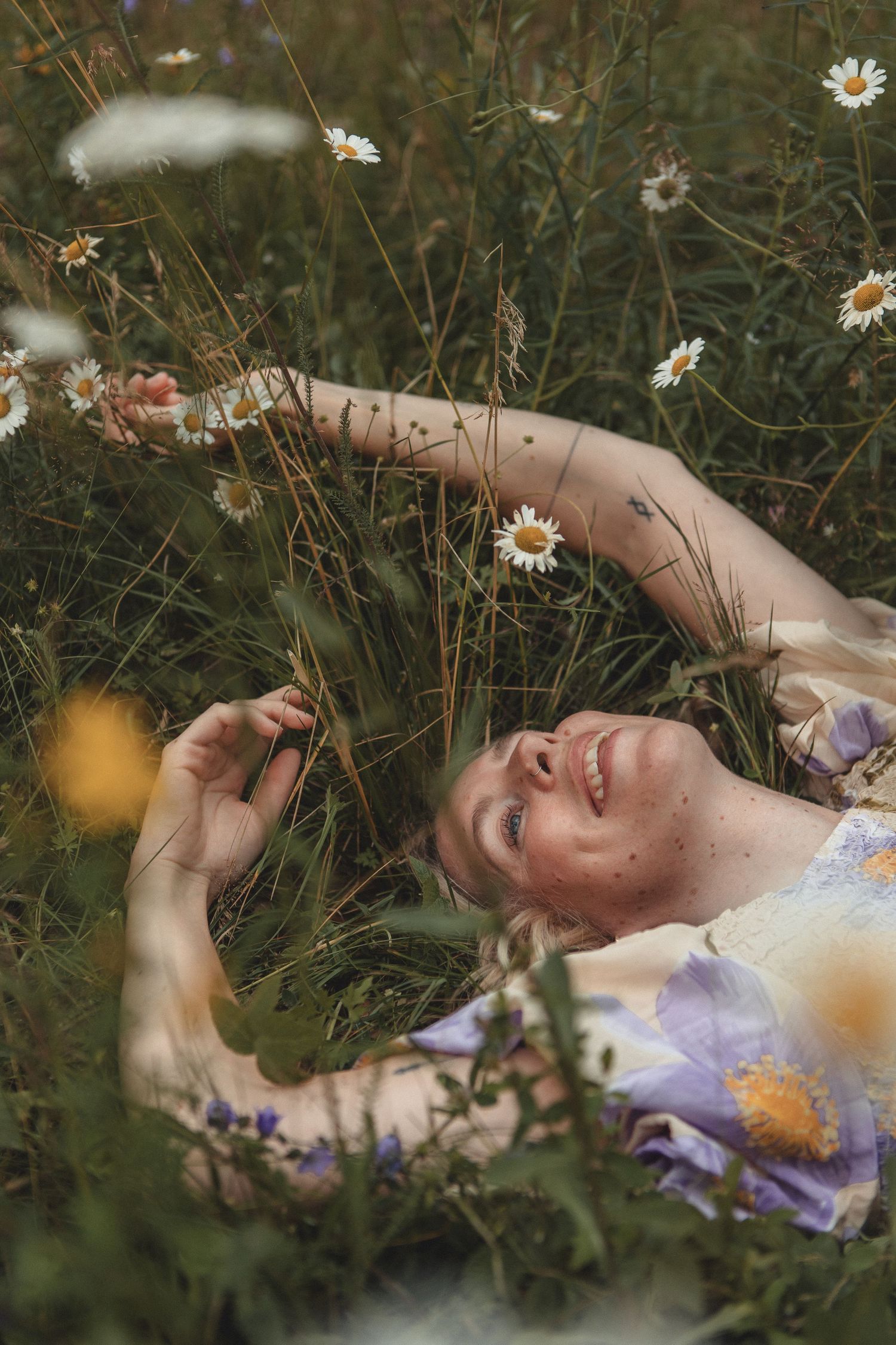 Dreamy portrait lying in wildflower meadow with daisies.