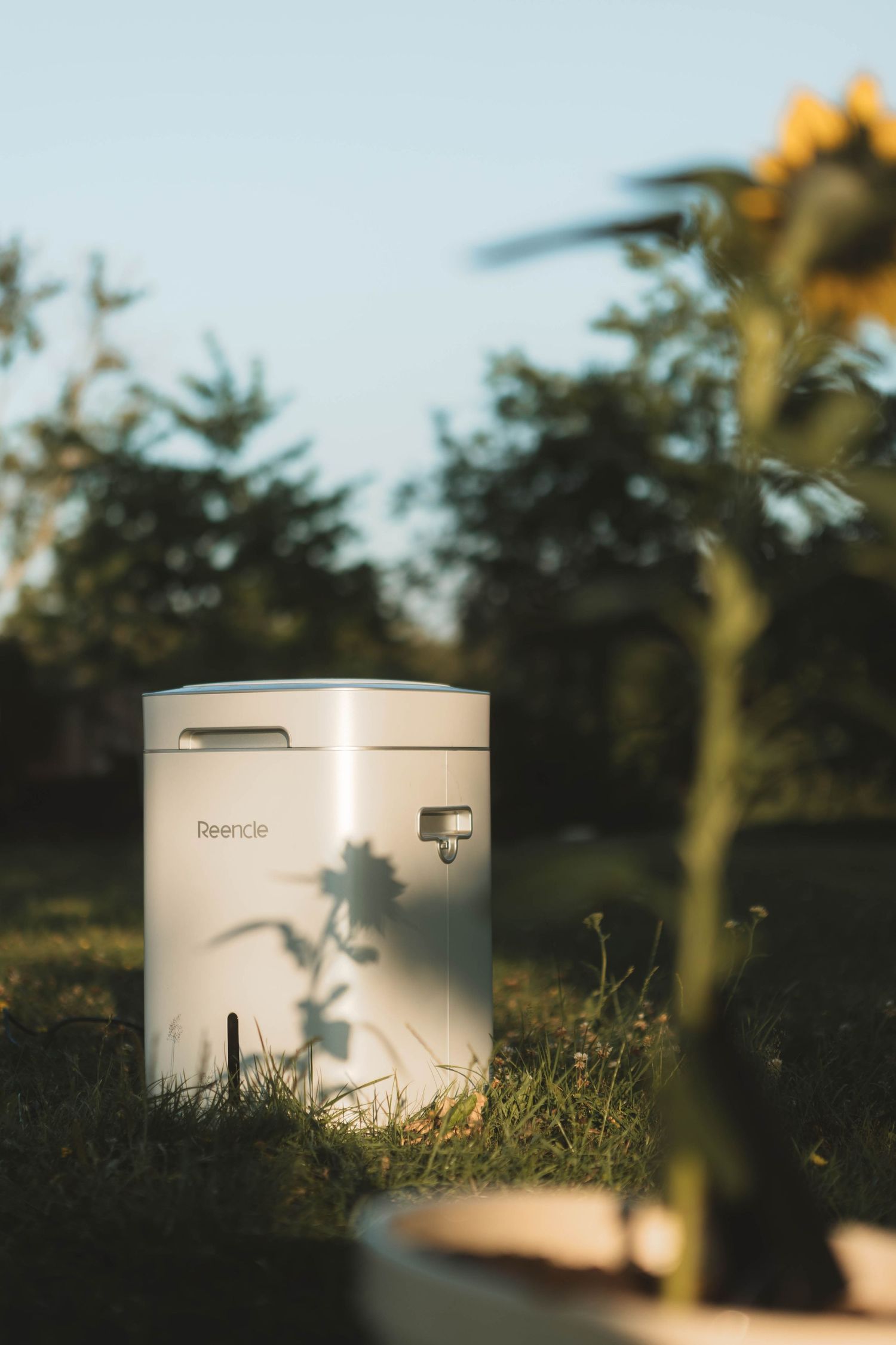 White cylindrical PVC pipe sections sit in golden sunlight-dappled grass against a blurred natural background.
