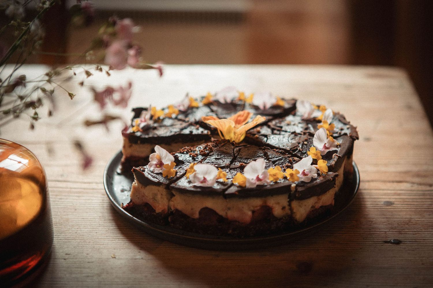 Dark chocolate torte garnished with orange flowers and decorative toppings.