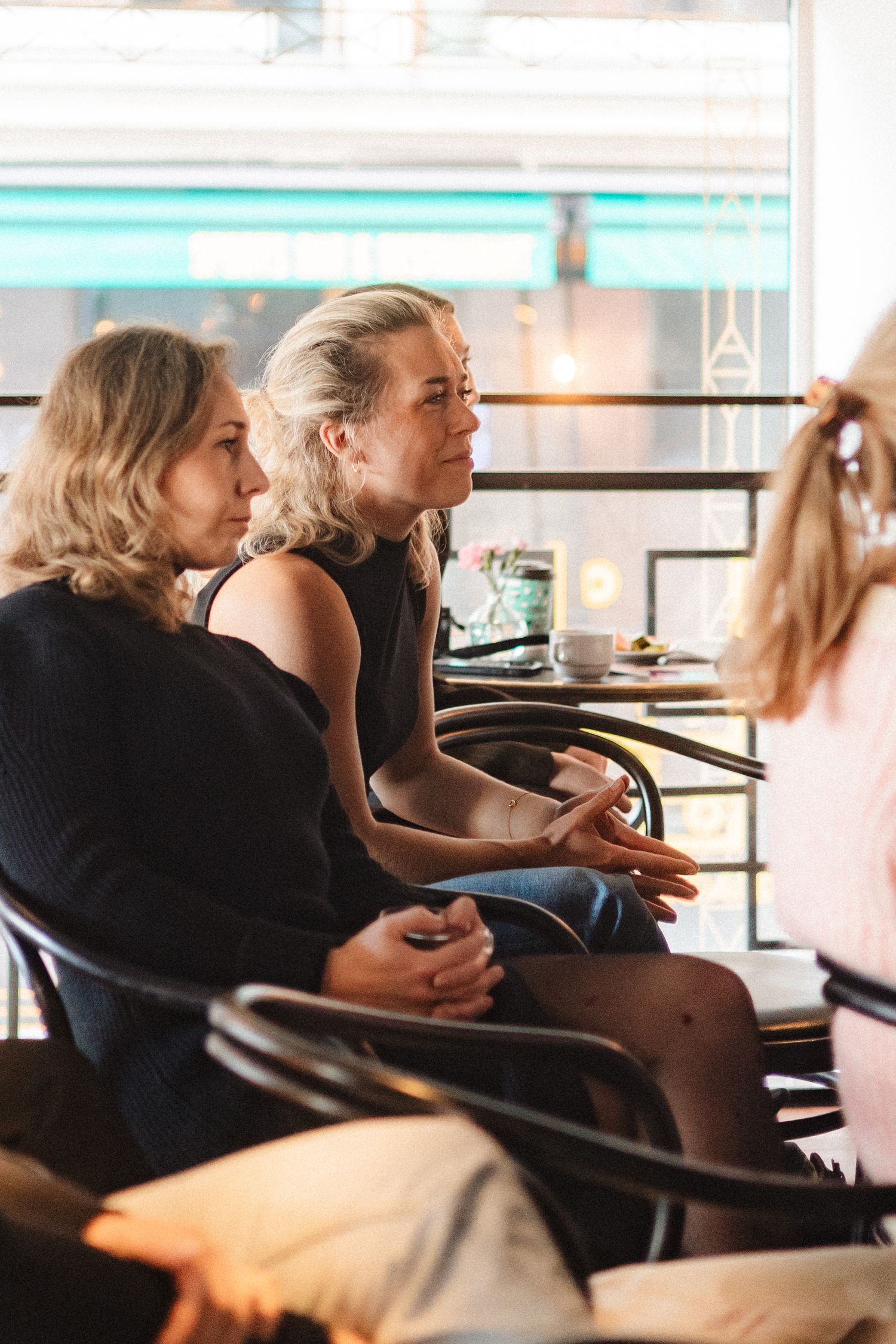 People having an engaged conversation while sitting in a casual cafe setting during daytime.