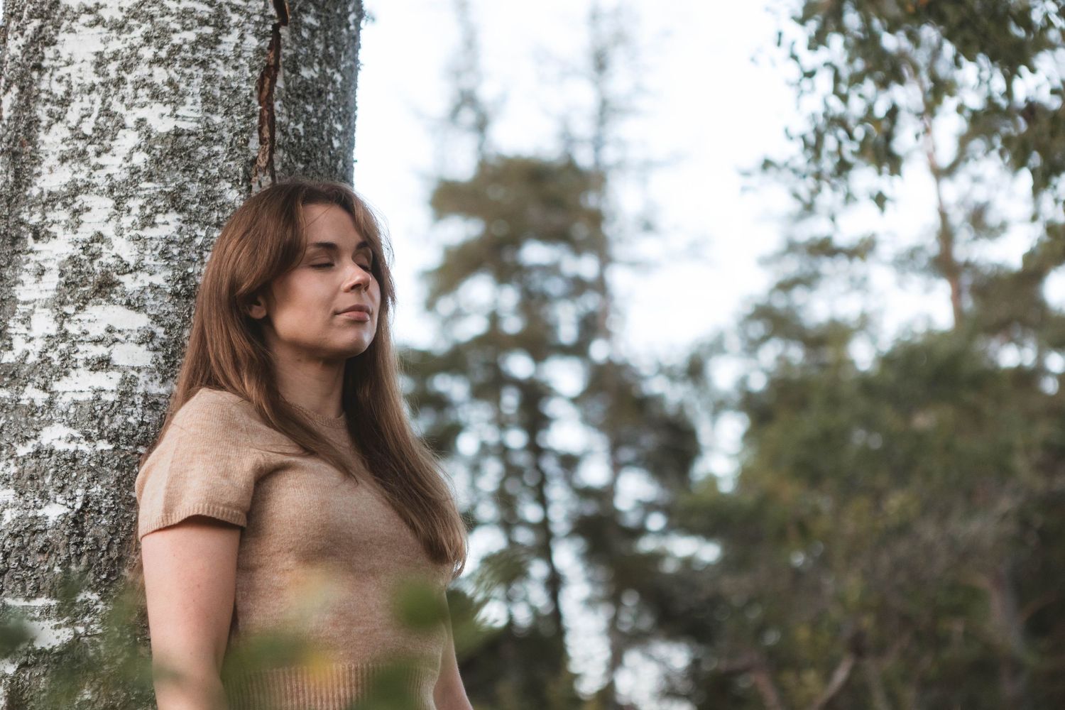 A series of photos showing someone posing against a birch tree trunk in a natural outdoor setting.