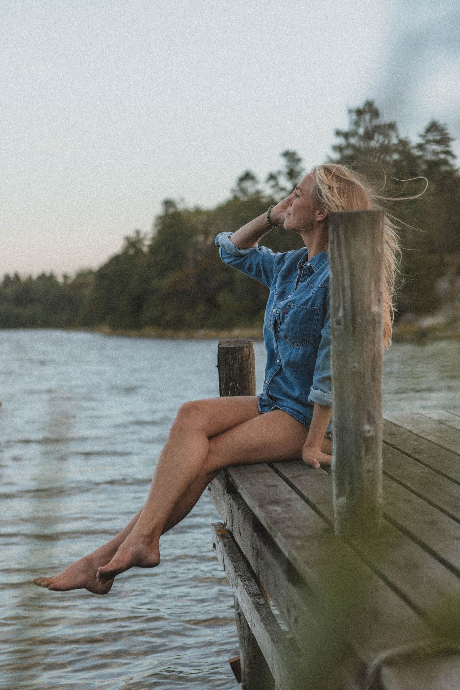 Relaxed summer portrait in denim on a dock with feet dangling over the water.