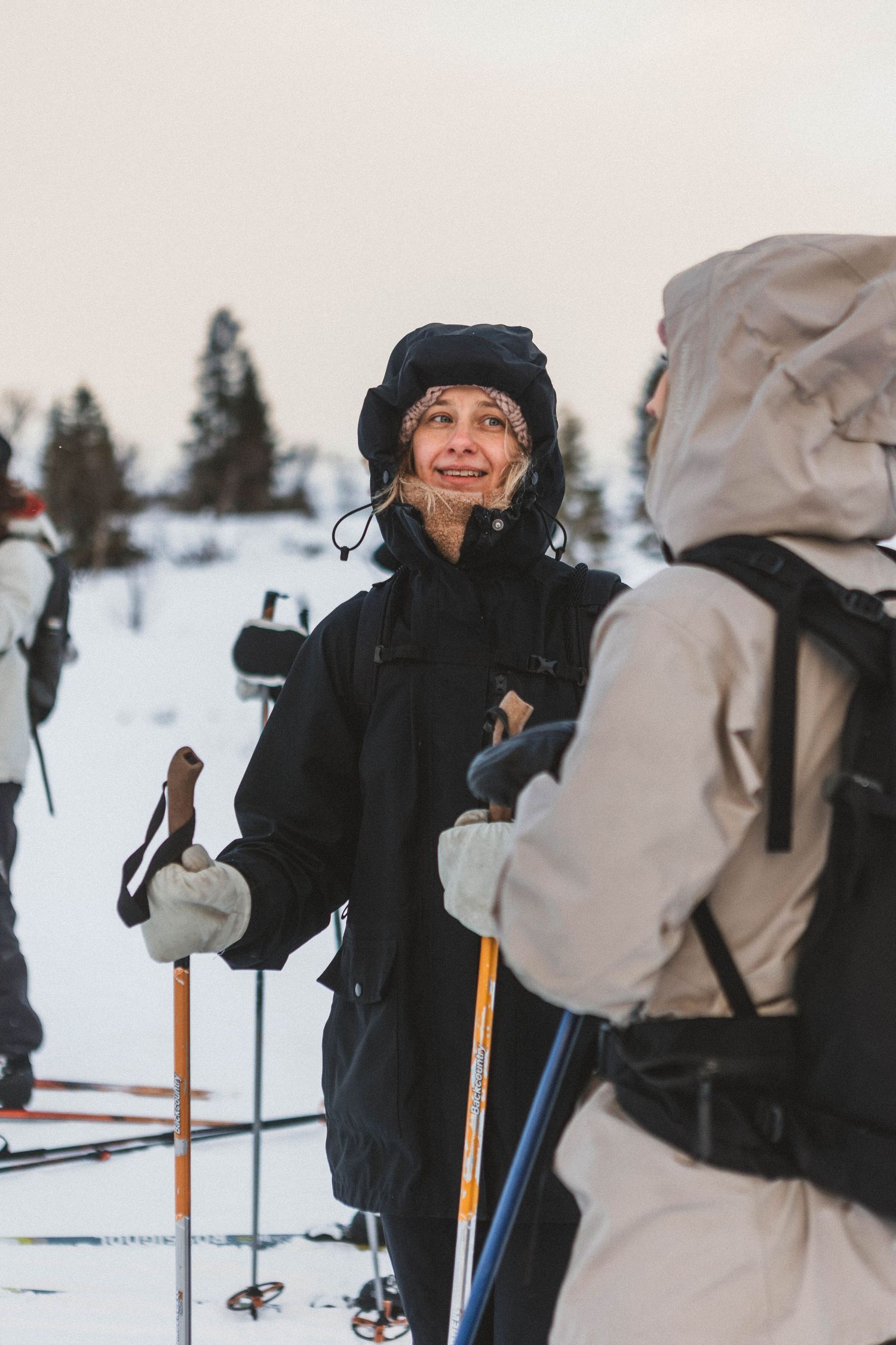 Winter scene of skiers taking a break in snowy landscape with ski poles.