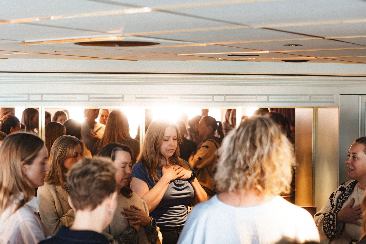 A crowded workshop or training session with participants gathered in a bright room with fluorescent lighting.