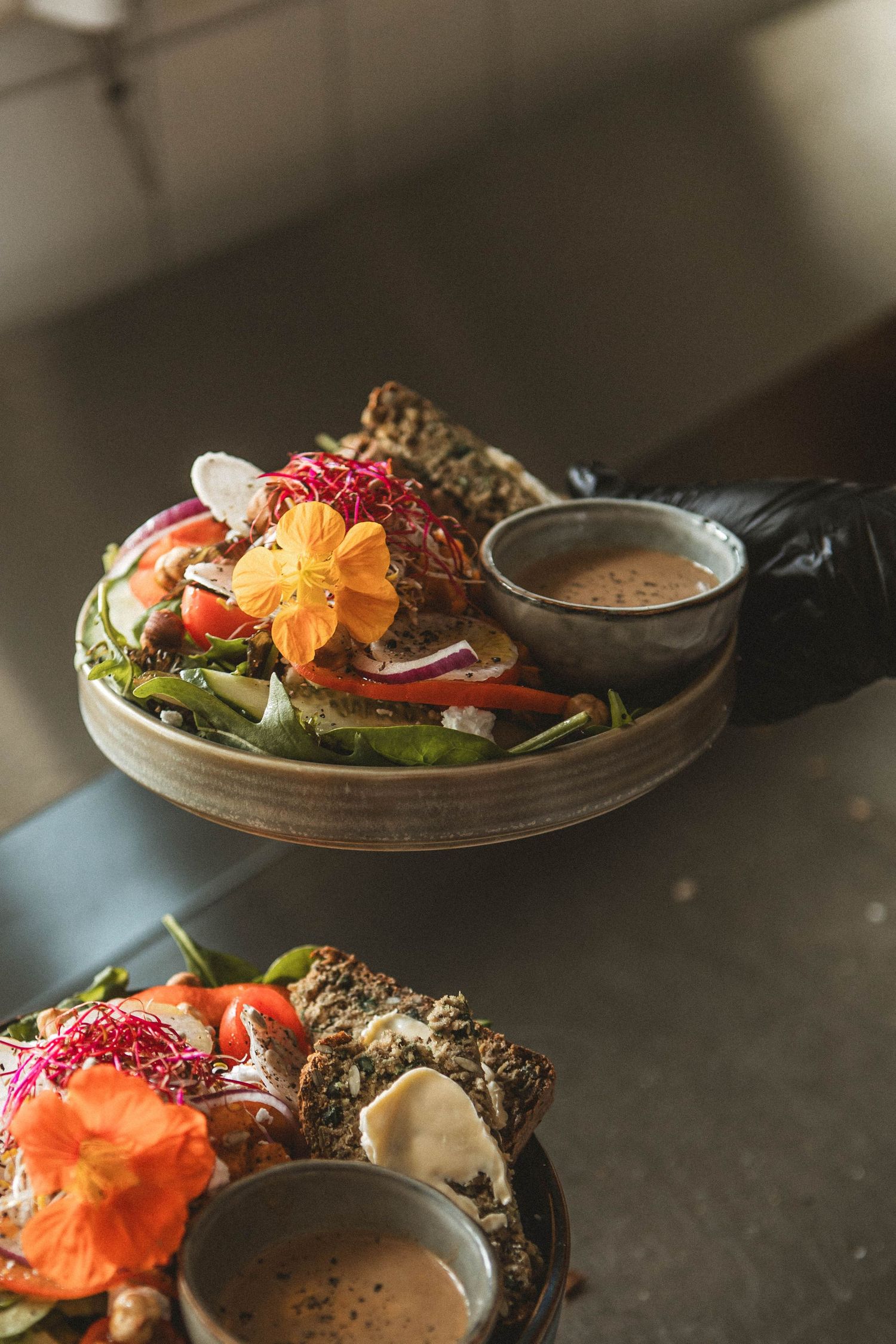 Fresh salad plate garnished with edible flowers and served with dipping sauce.