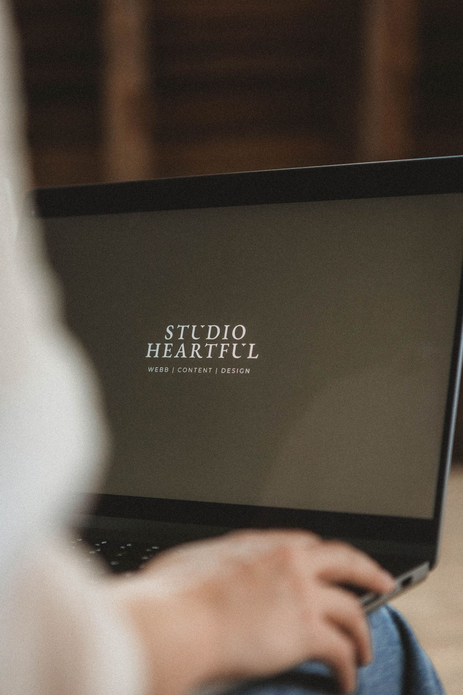 Close-up shot of laptop displaying 'STUDIO' and 'HEARTFUL' text on dark background.