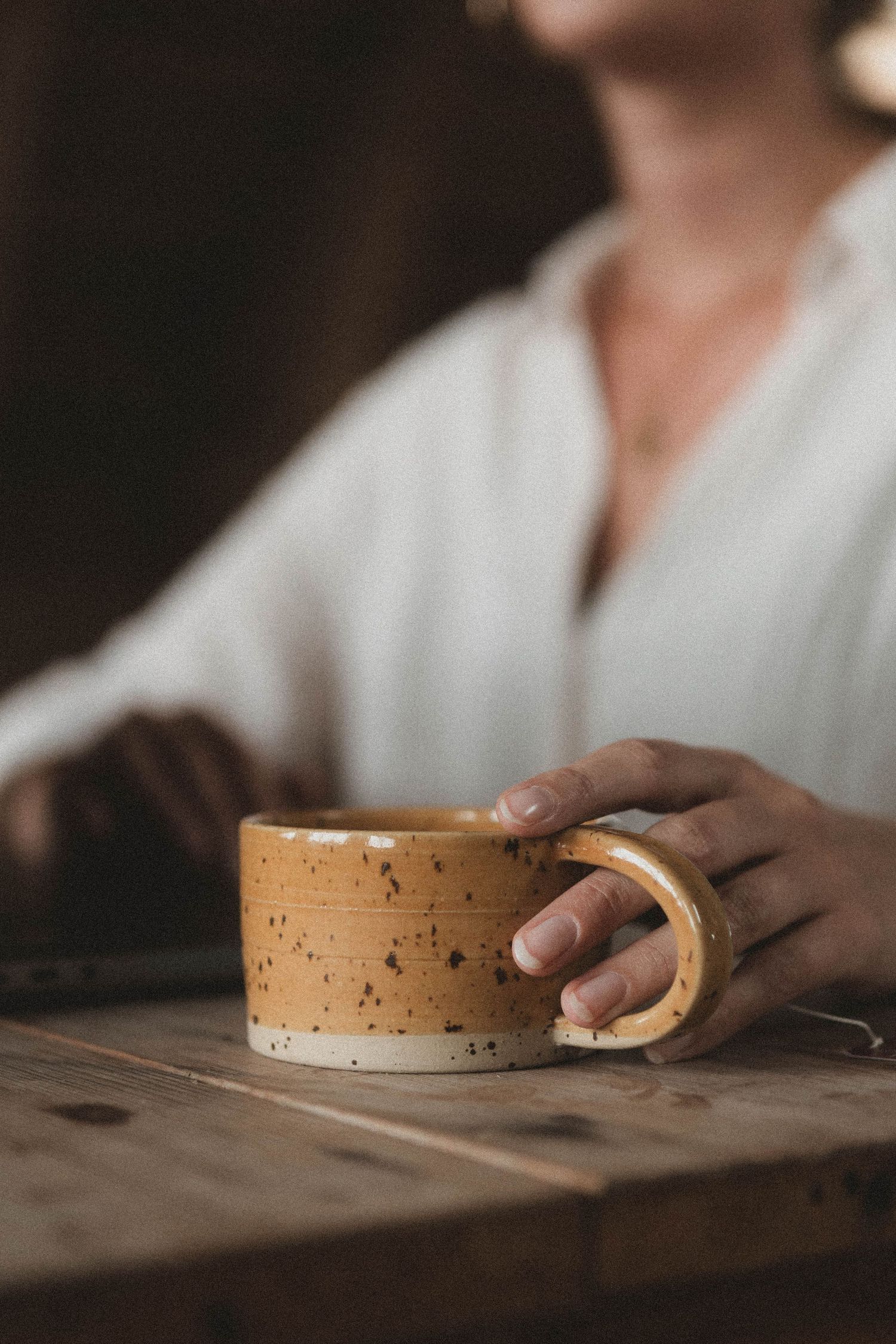 Hands holding and examining a cork coaster on wooden surface in warm lighting.