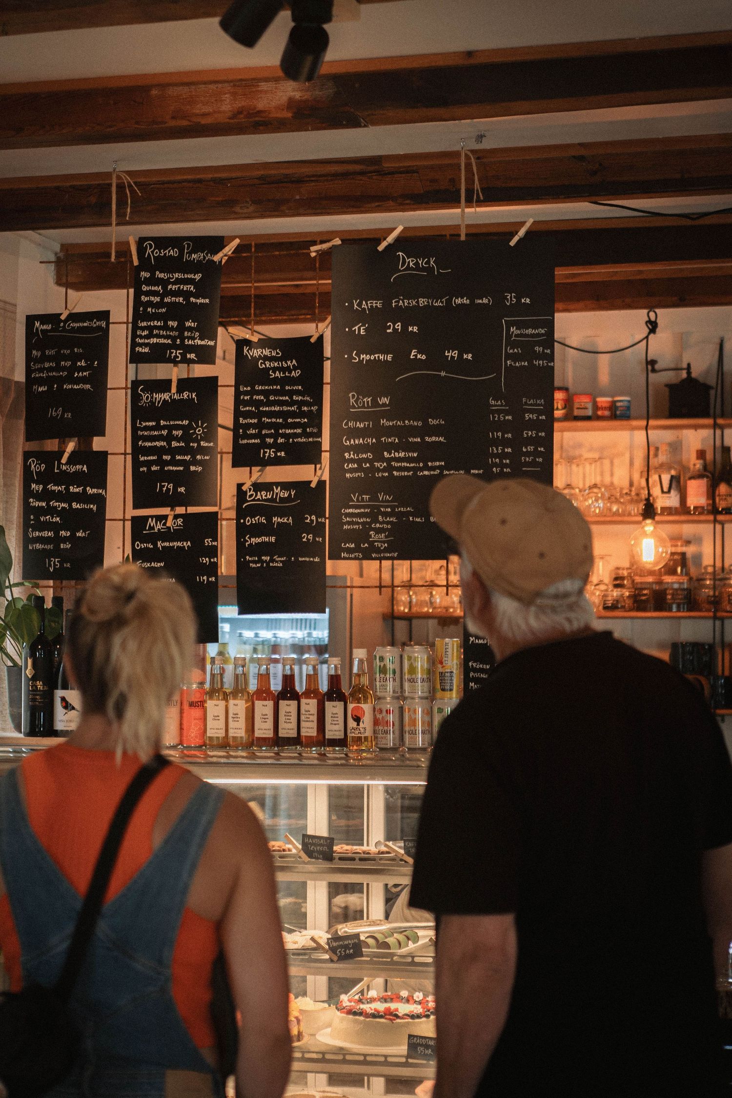 Customers viewing menu boards and display cases in a cozy cafe interior.