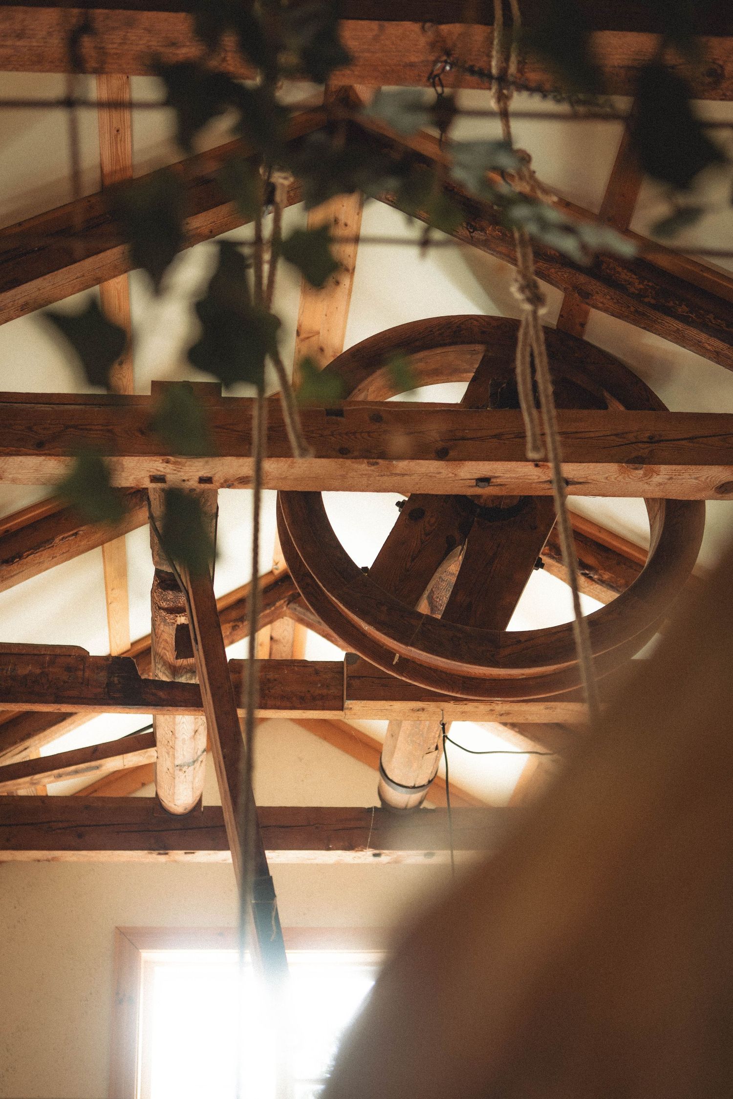 Rustic wooden wheel mechanism visible in ceiling beams with atmospheric lighting.