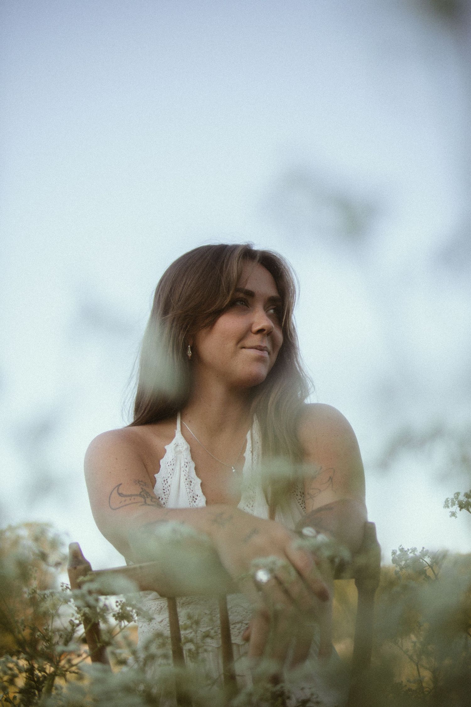 A dreamy portrait of a person among wildflowers against a soft, blurred natural background.