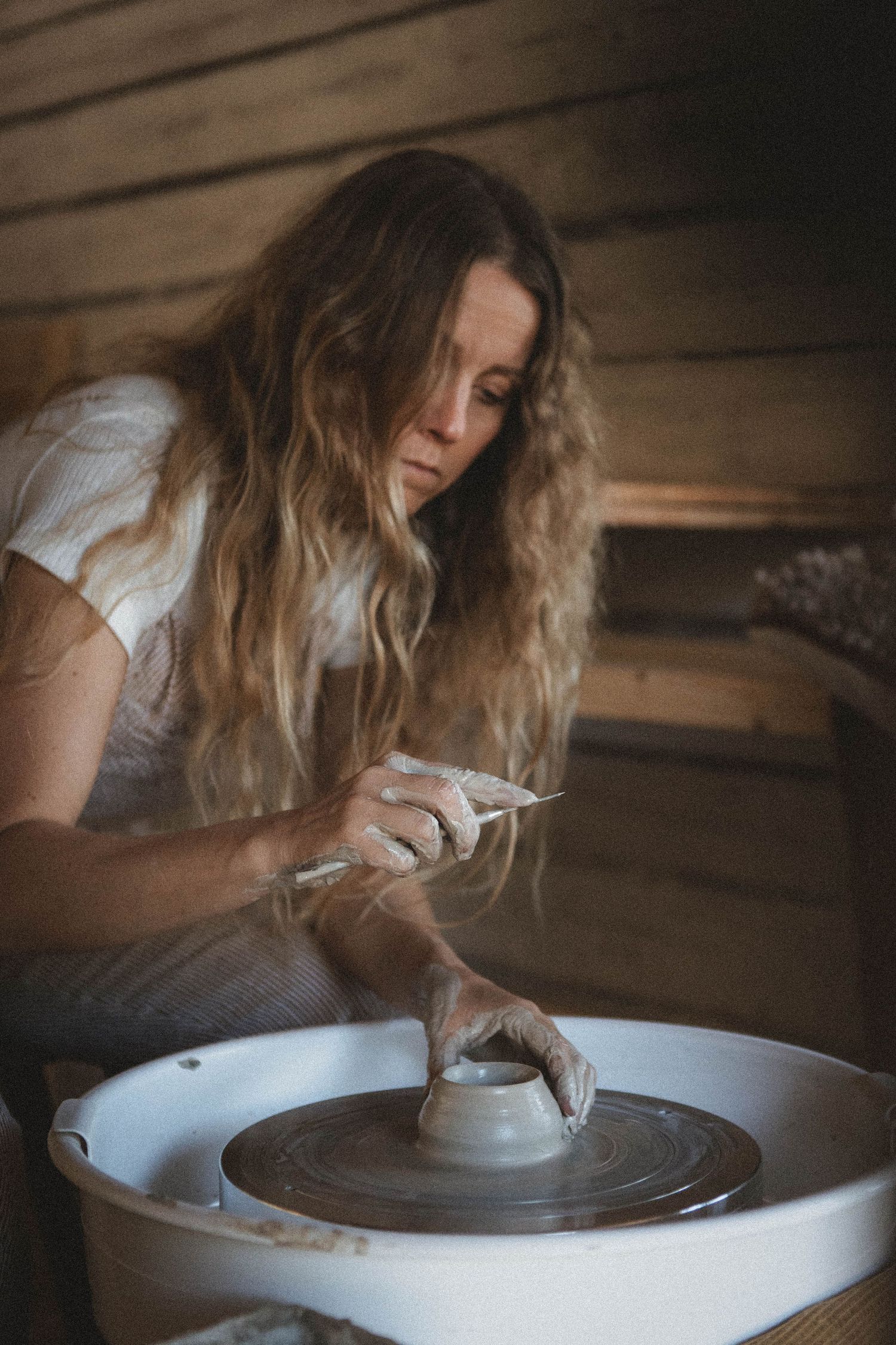 Artisan working with clay on a pottery wheel in a rustic wooden studio.