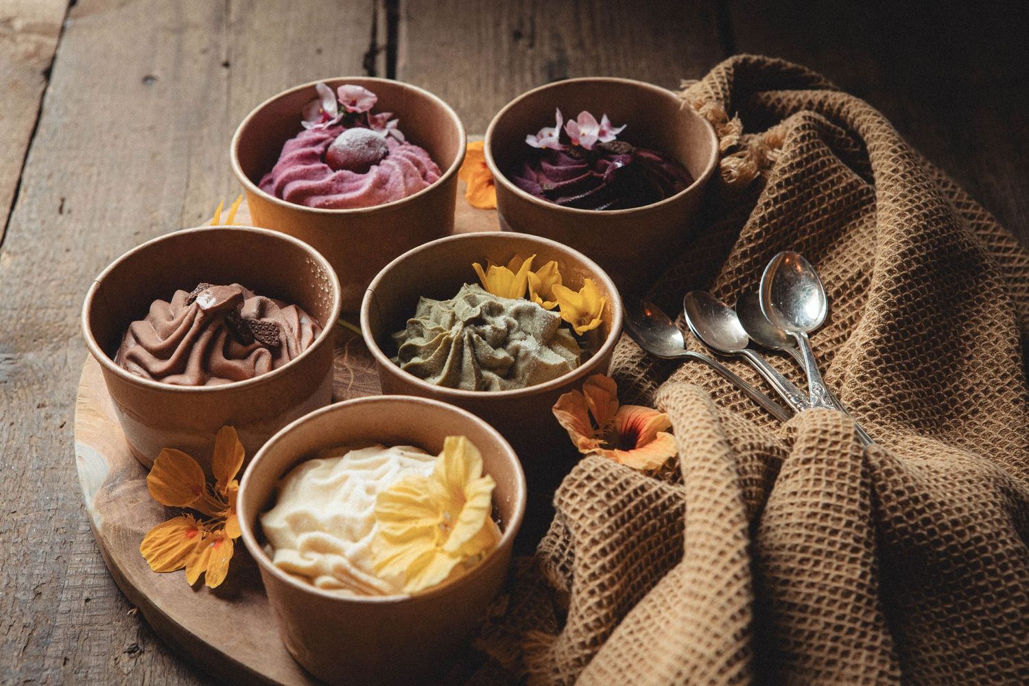 Handcrafted ice cream display featuring multiple flavors in wooden bowls with rustic styling.
