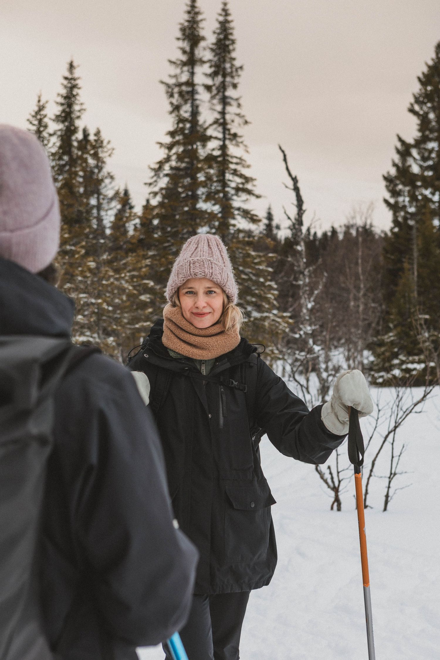 Cross-country skiers stopping along snowy forest trail in winter.