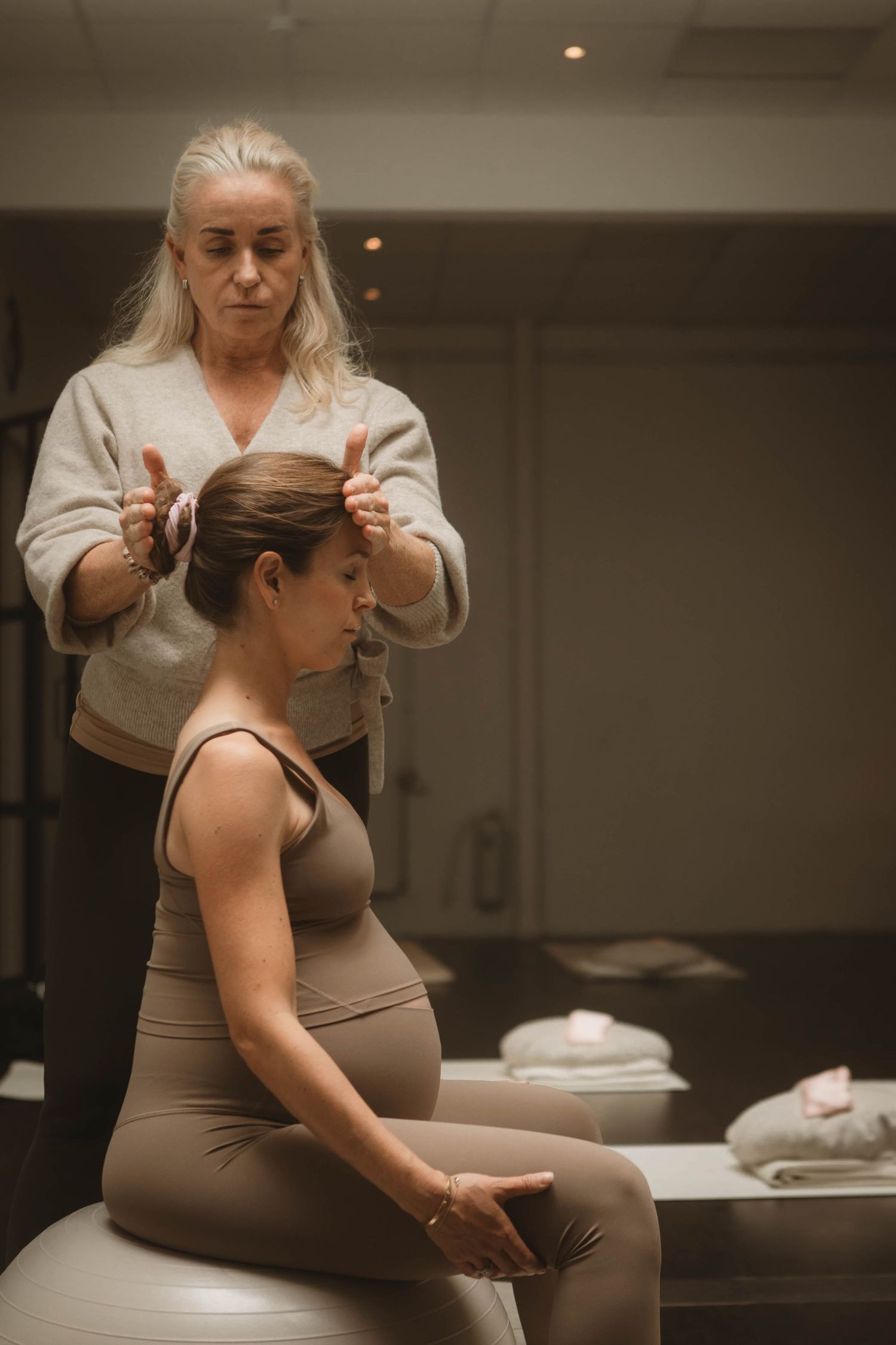 A woman receives therapeutic massage while sitting during a pregnancy wellness session.