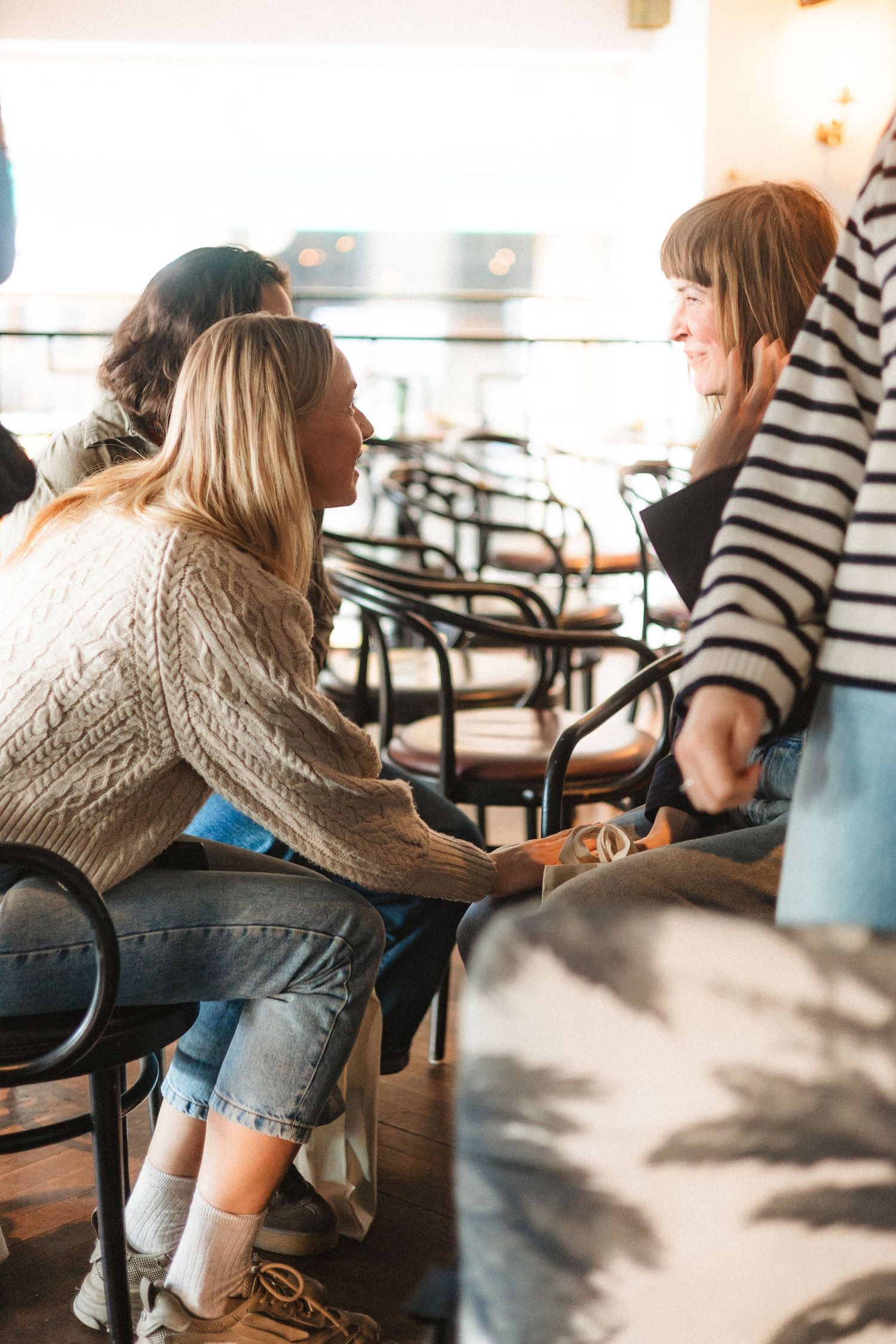 A sequence of photos showing someone in a beige sweater and jeans leaning forward at a cafe table.