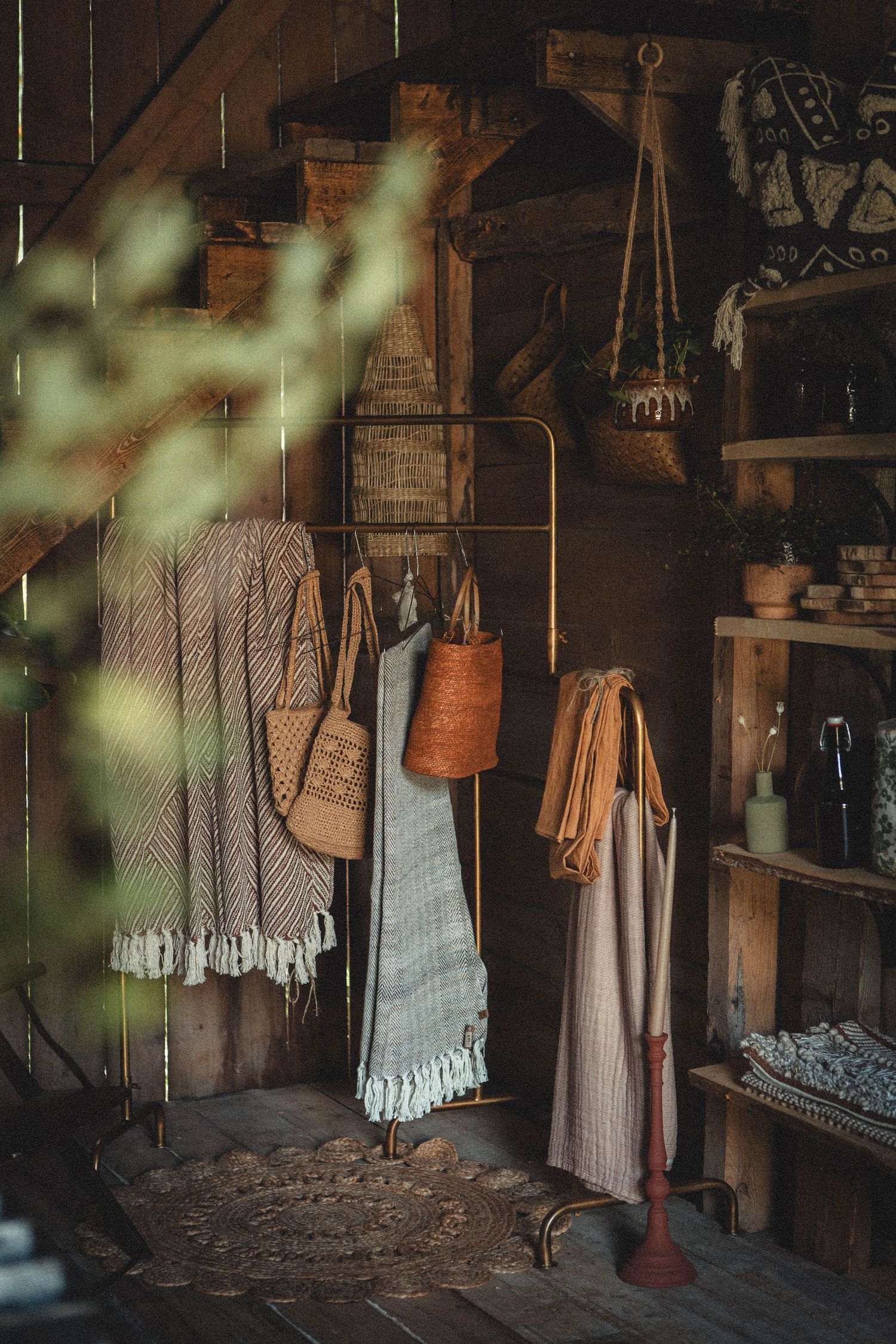 Rustic storage area with hanging textiles, woven baskets and vintage decor items in a wooden interior.