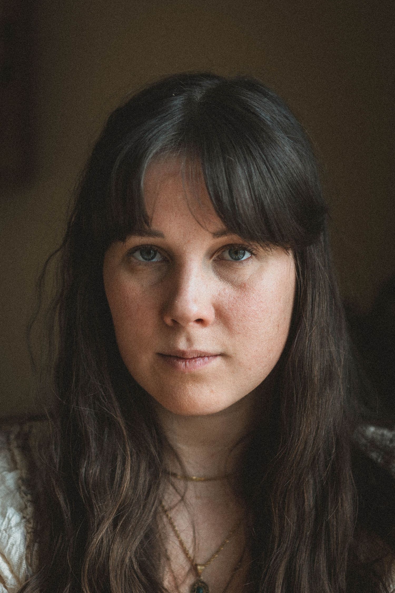 Intimate portrait with natural lighting and delicate jewelry.
