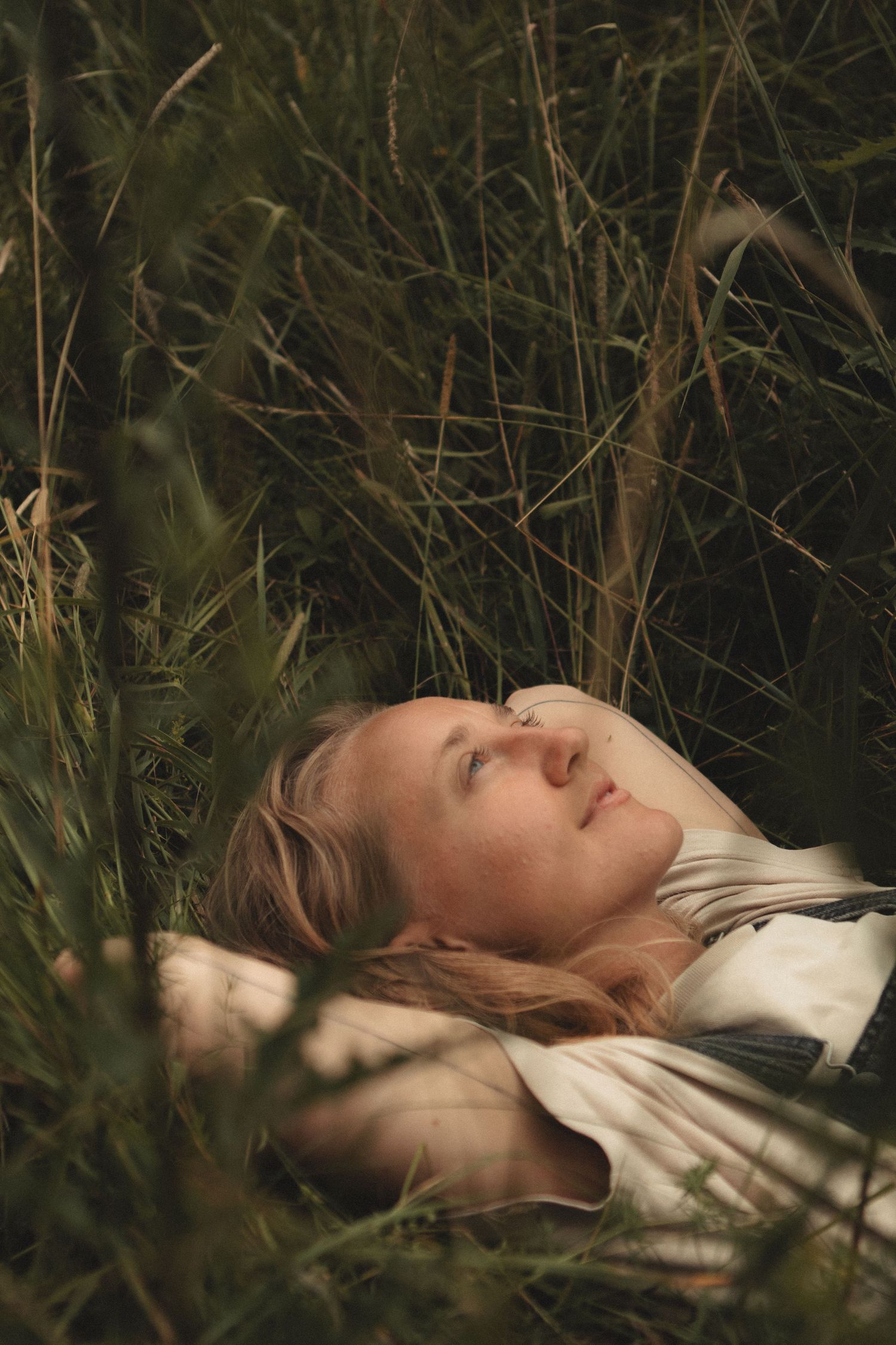Relaxing figure resting in long grass with dreamy summer afternoon lighting.
