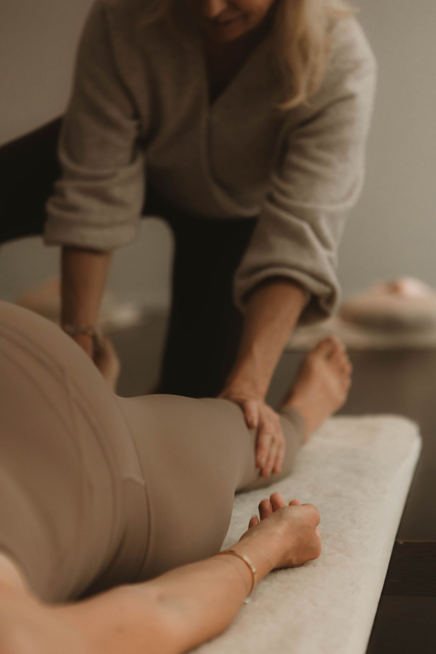 Therapeutic massage session showing practitioner's hands working on client on treatment table.