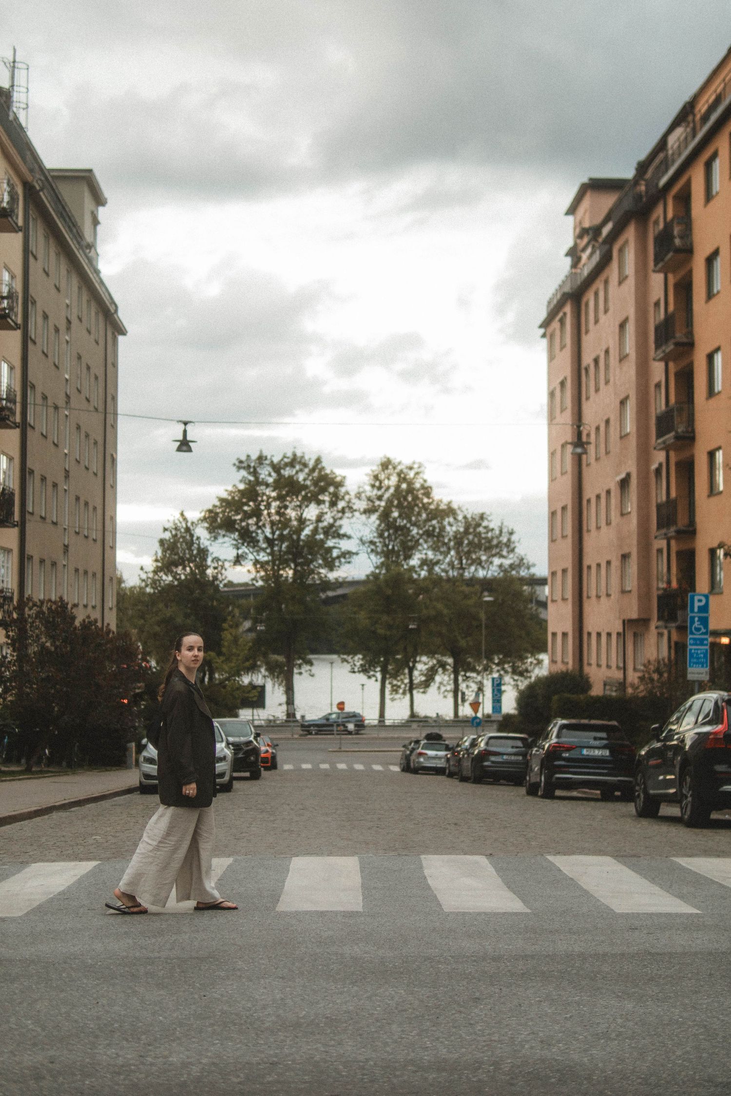 Person crossing an urban street on a crosswalk between apartment buildings in Stockholm on an overcast day.