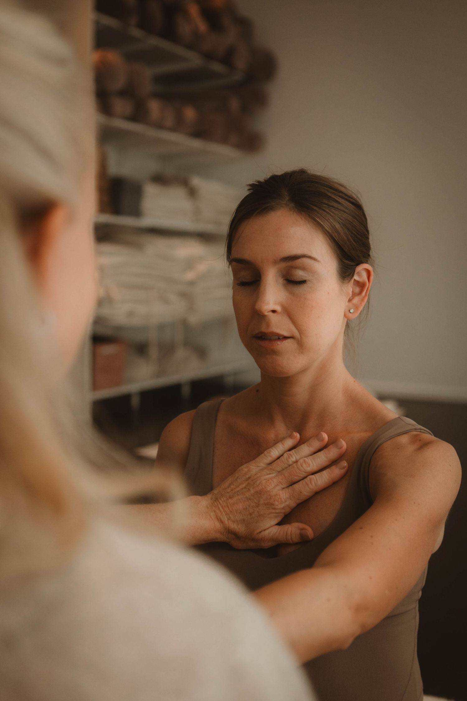 Two people during a therapeutic session with one person placing their hand on their chest.