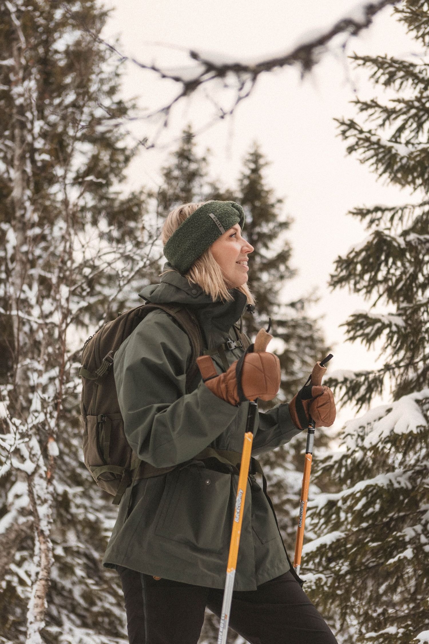 Winter hiker with backpack and poles enjoying snowy forest landscape.