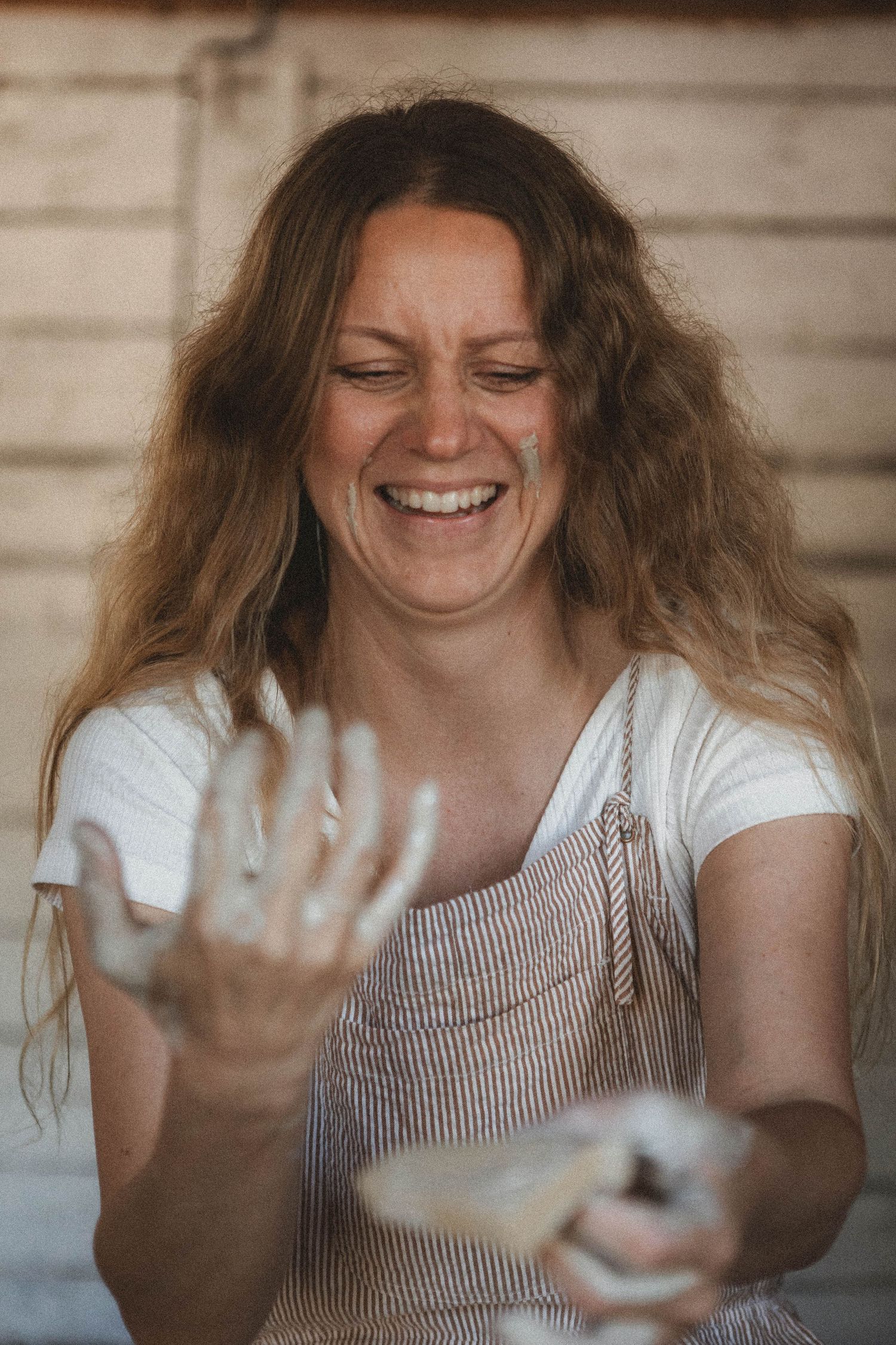 Clay-covered hands show the joyful mess of pottery making in a rustic studio.