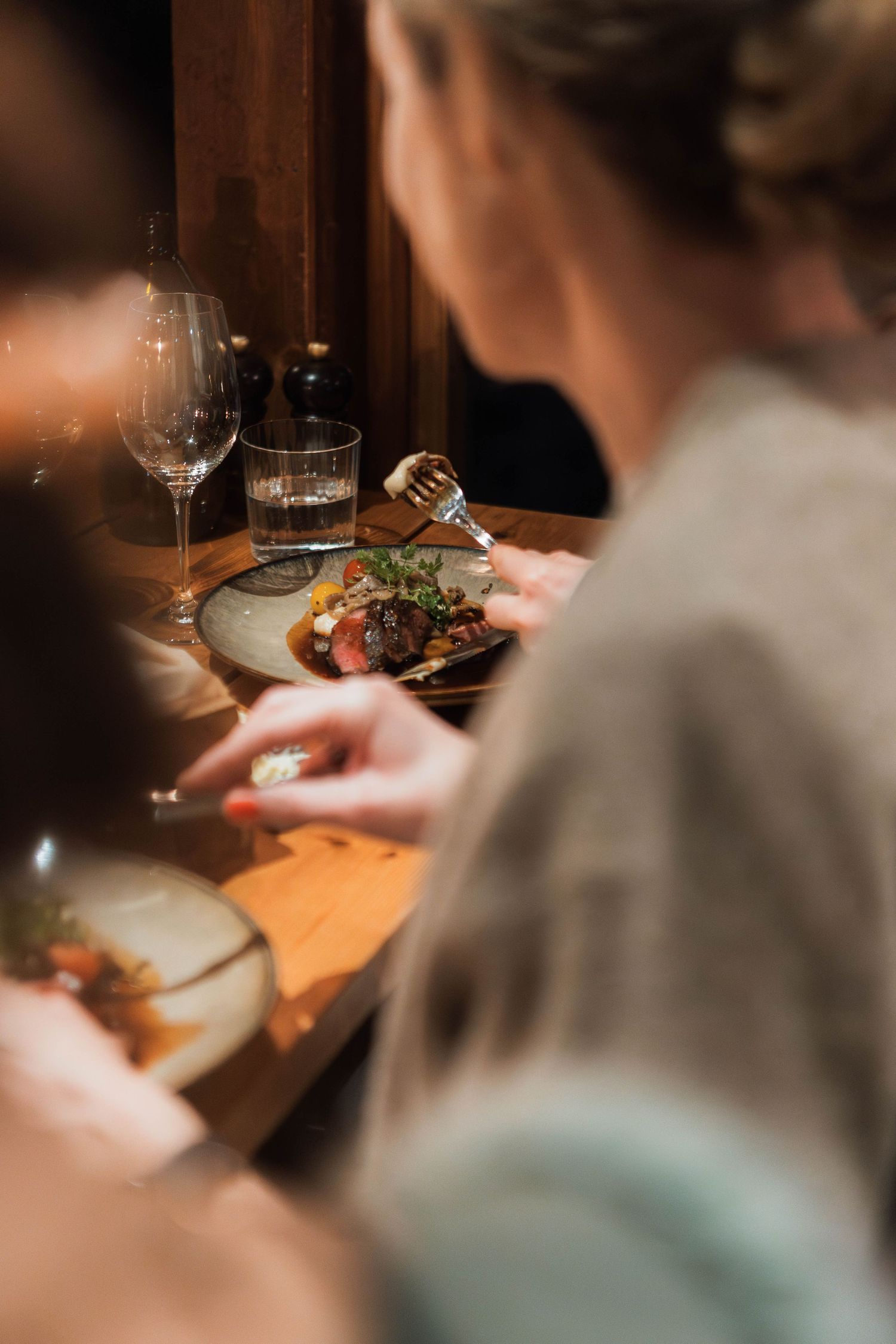 Close-up of fine dining experience with wine glass and plated gourmet meal.