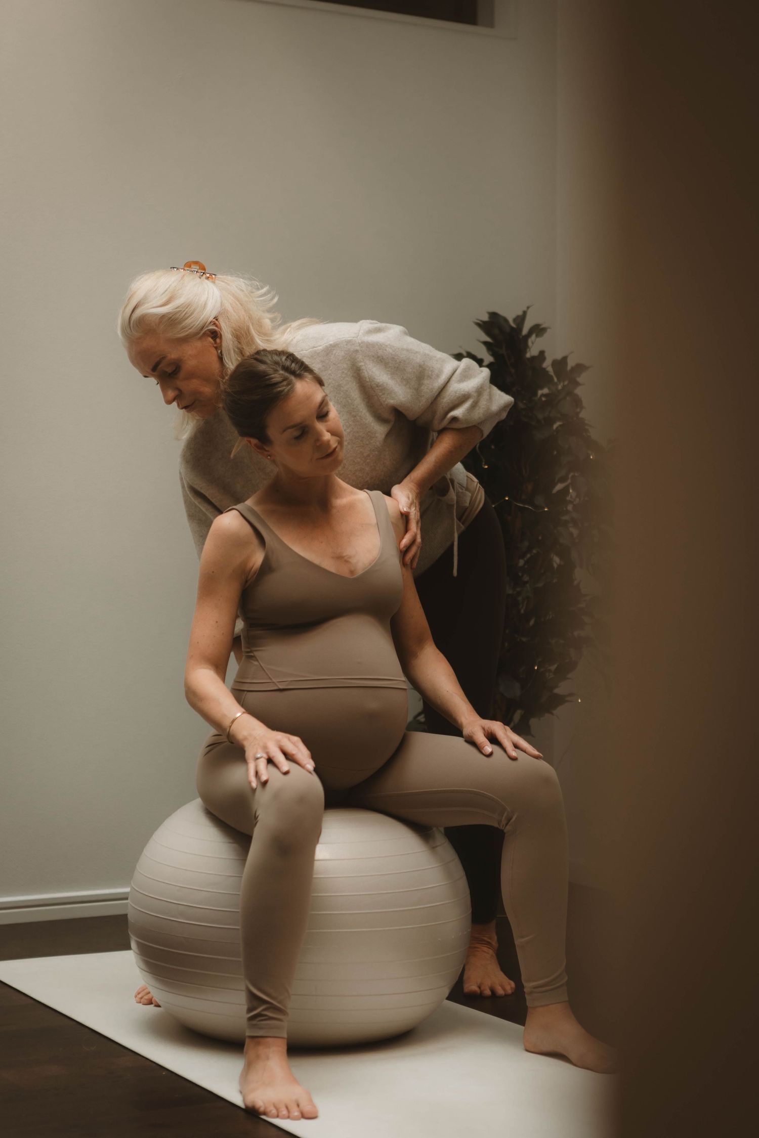 A prenatal massage session with two people using an exercise ball for support.