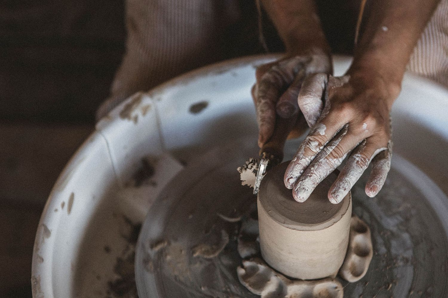 Close-up shot of hands working with clay on pottery wheel in dimly lit studio.