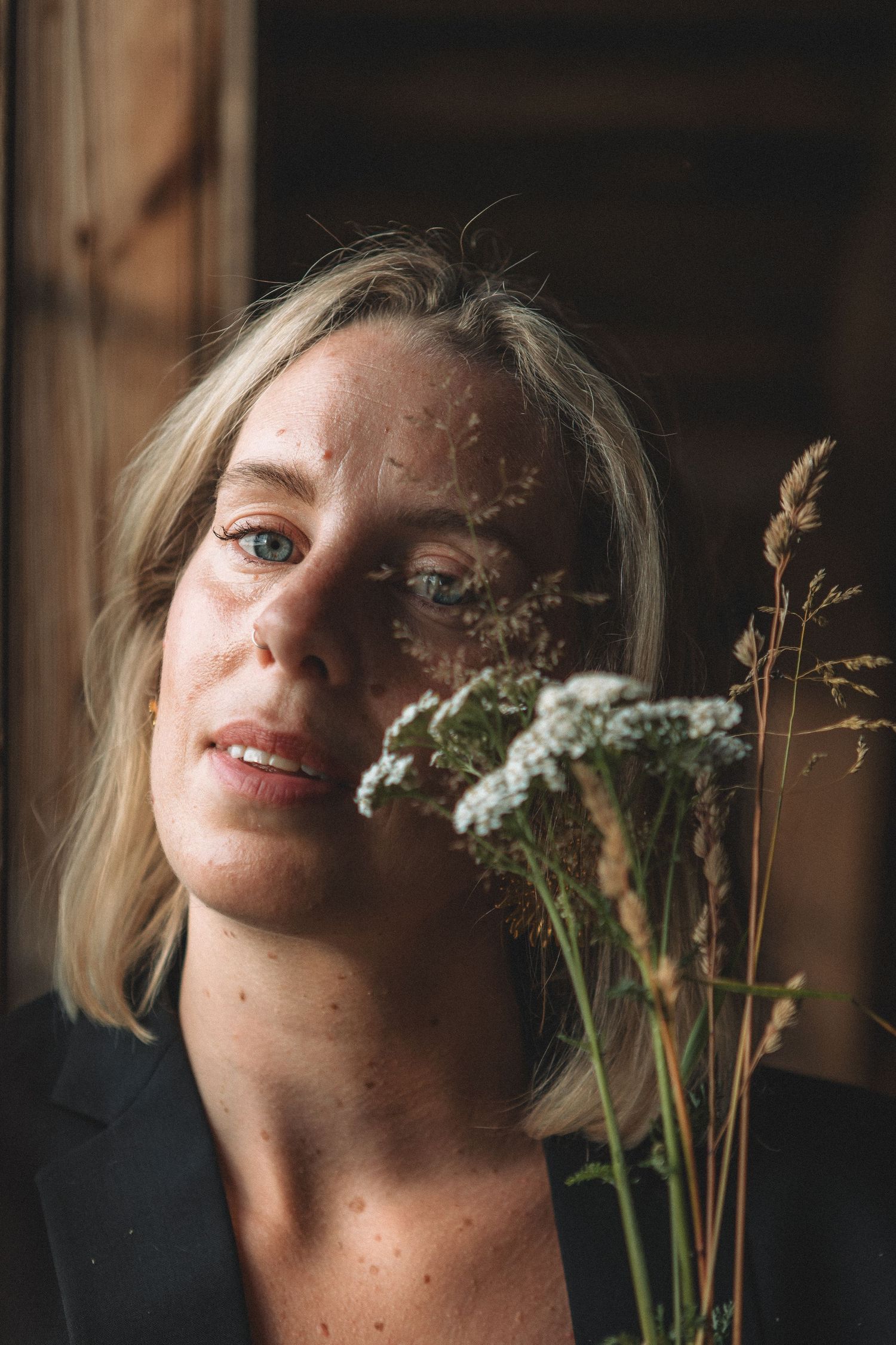 Artistic portrait with delicate wildflowers against rustic wooden background.