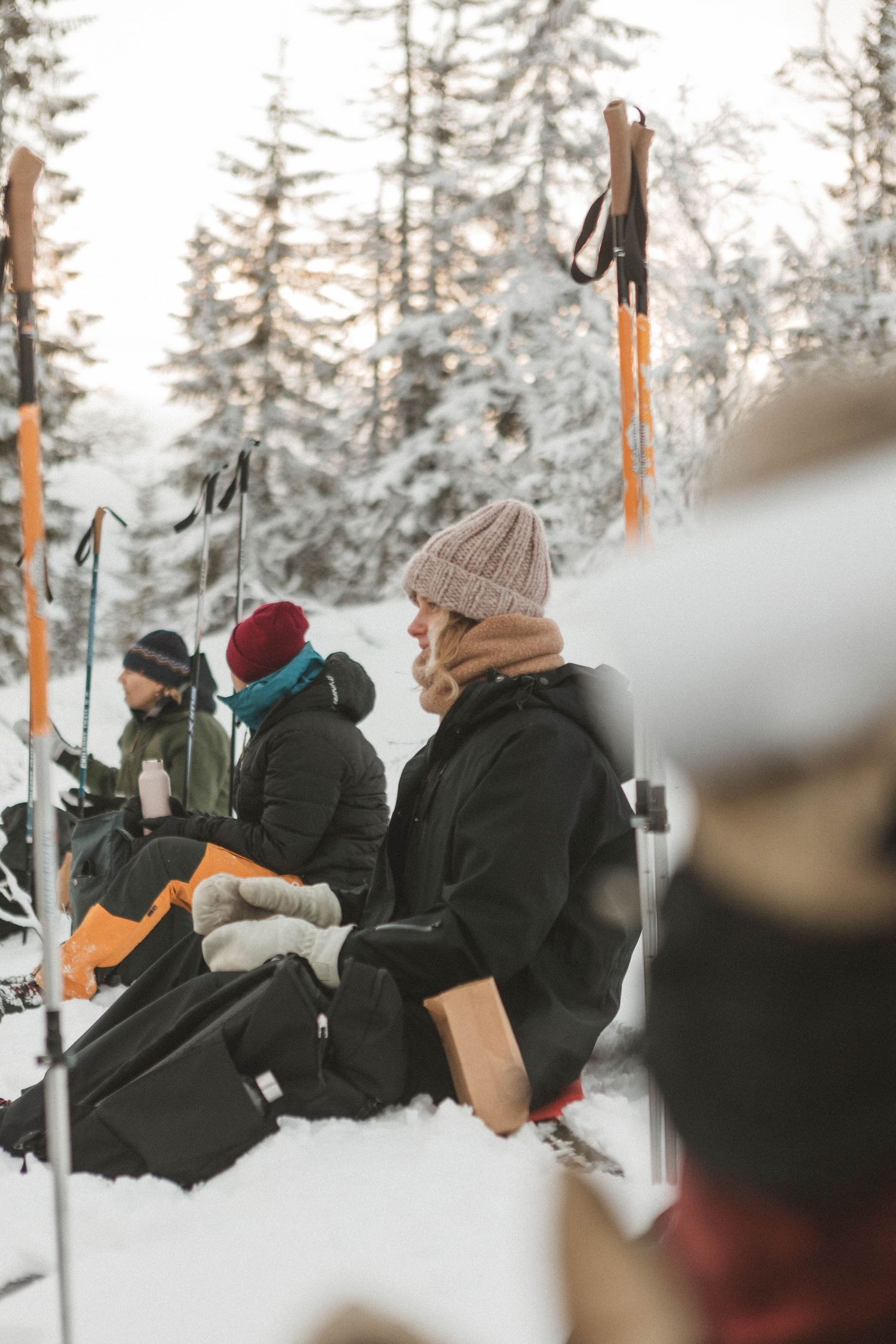 Winter scene with skiers taking a break in snowy forest with ski poles and equipment.