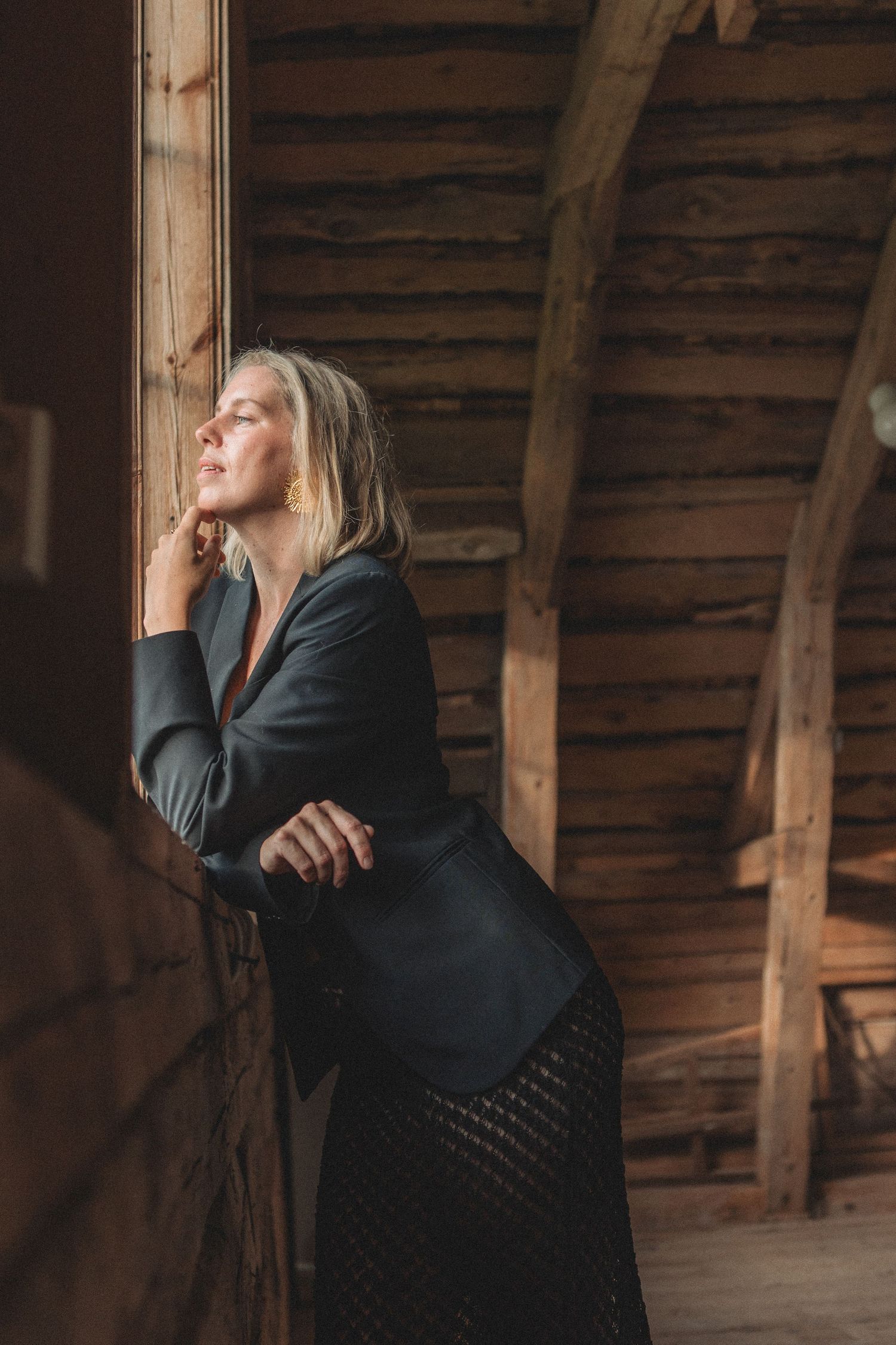 Atmospheric portrait in a rustic wooden building with moody lighting and dark clothing.