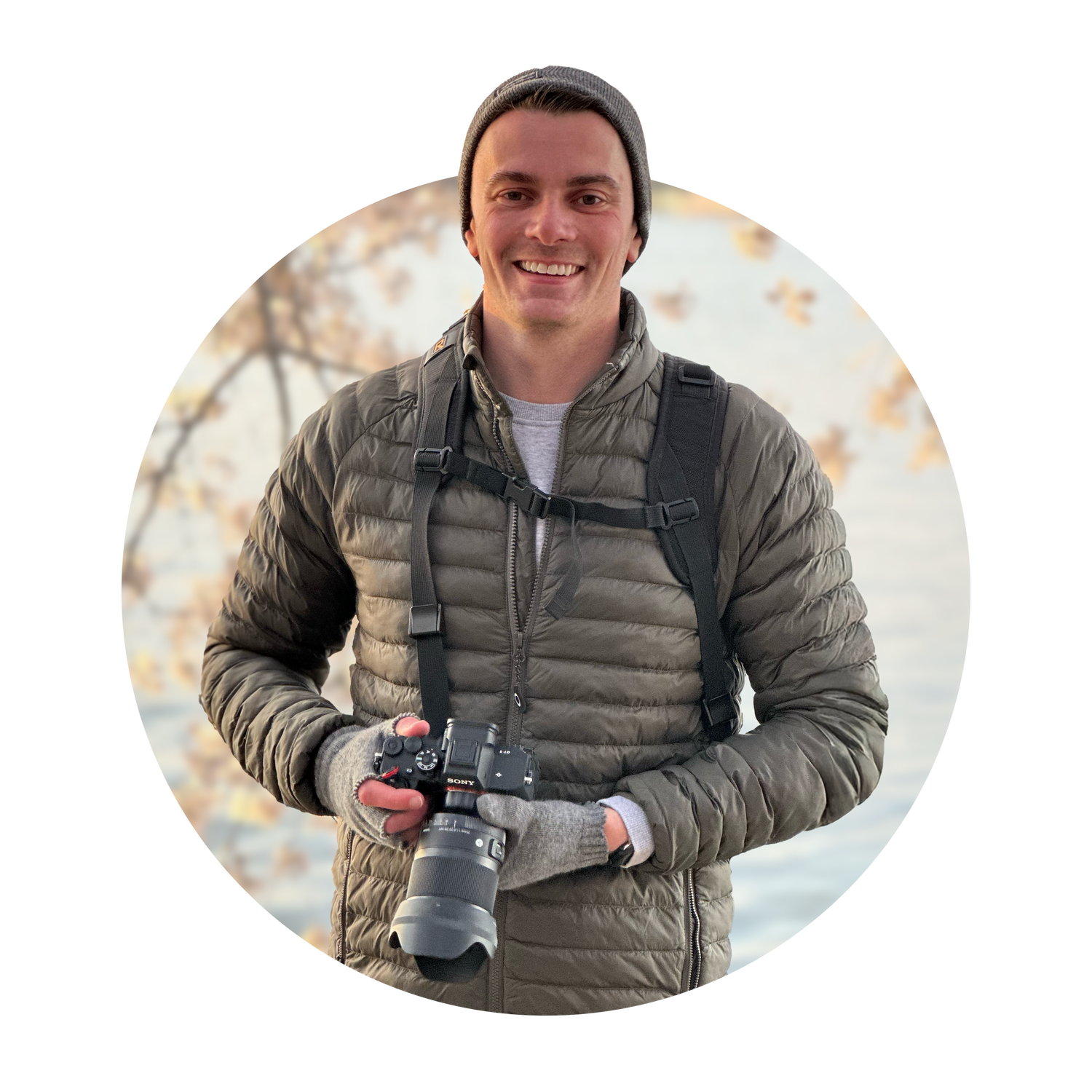 Professional photographer wearing grey puffer jacket holding camera equipment.