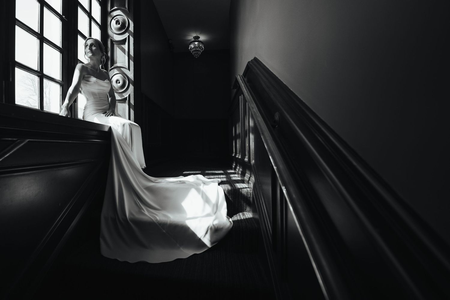 A dramatic black and white wedding photography series showing a bride in a flowing gown on a grand staircase.